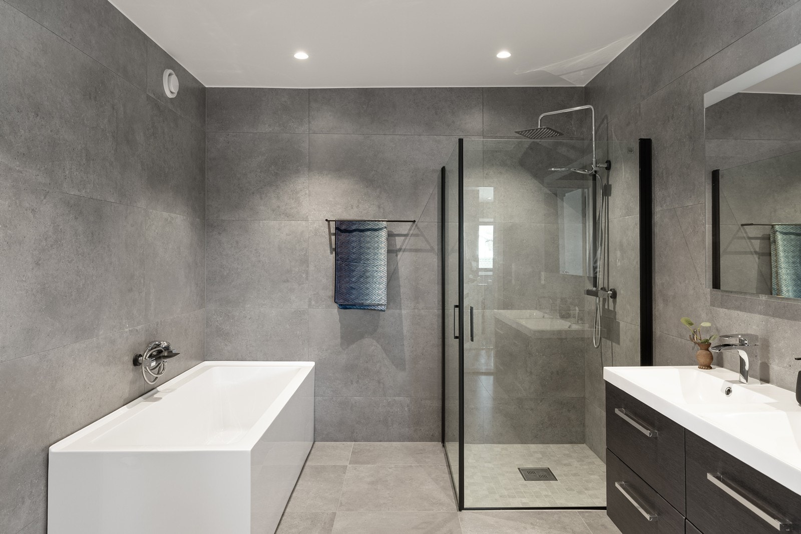Badet er utstyrt med både badekar og dusj med glassvegger, vegghengt toalett samt en stilren dobbel servantinnredning. Galleribilde