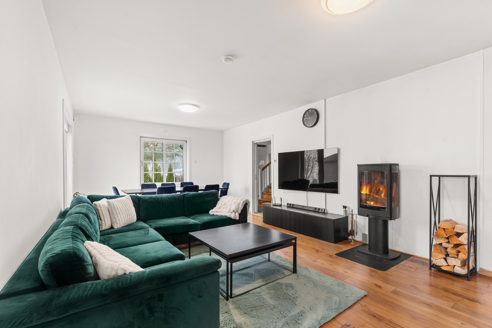 Tv-stuen fremstår som romslig og innbydende, med god plass til både sofagruppe og spisebord. Peisovnen tilfører varme og en lun stemning. Galleribilde