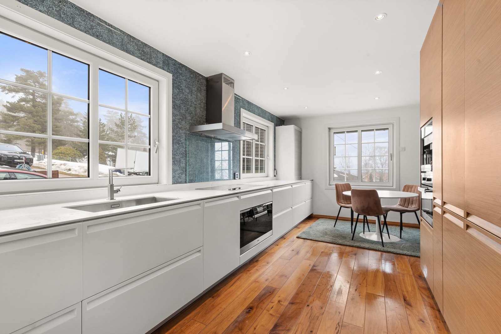 Kjøkkeninnredningen har glatte og strukturerte fronter som skaper et moderne preg, og er utstyrt med integrerte hvitevarer som fritthengende ventilator, induksjonstopp, stekeovn på 90 cm, mikroovn, kaffemaskin og kjøleskap med fryser. Galleribilde