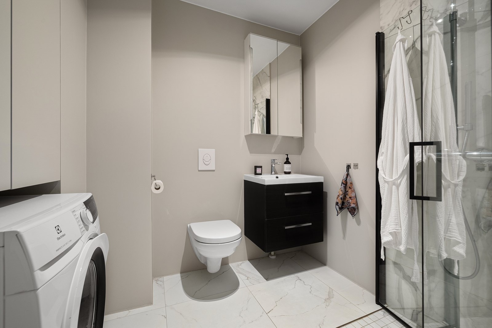 Leilighetens bad er lekkert gjennomført og innredet med servant med underskap, speil med skap, innbygd skap, vegghengt WC og dusjhjørne. Galleribilde