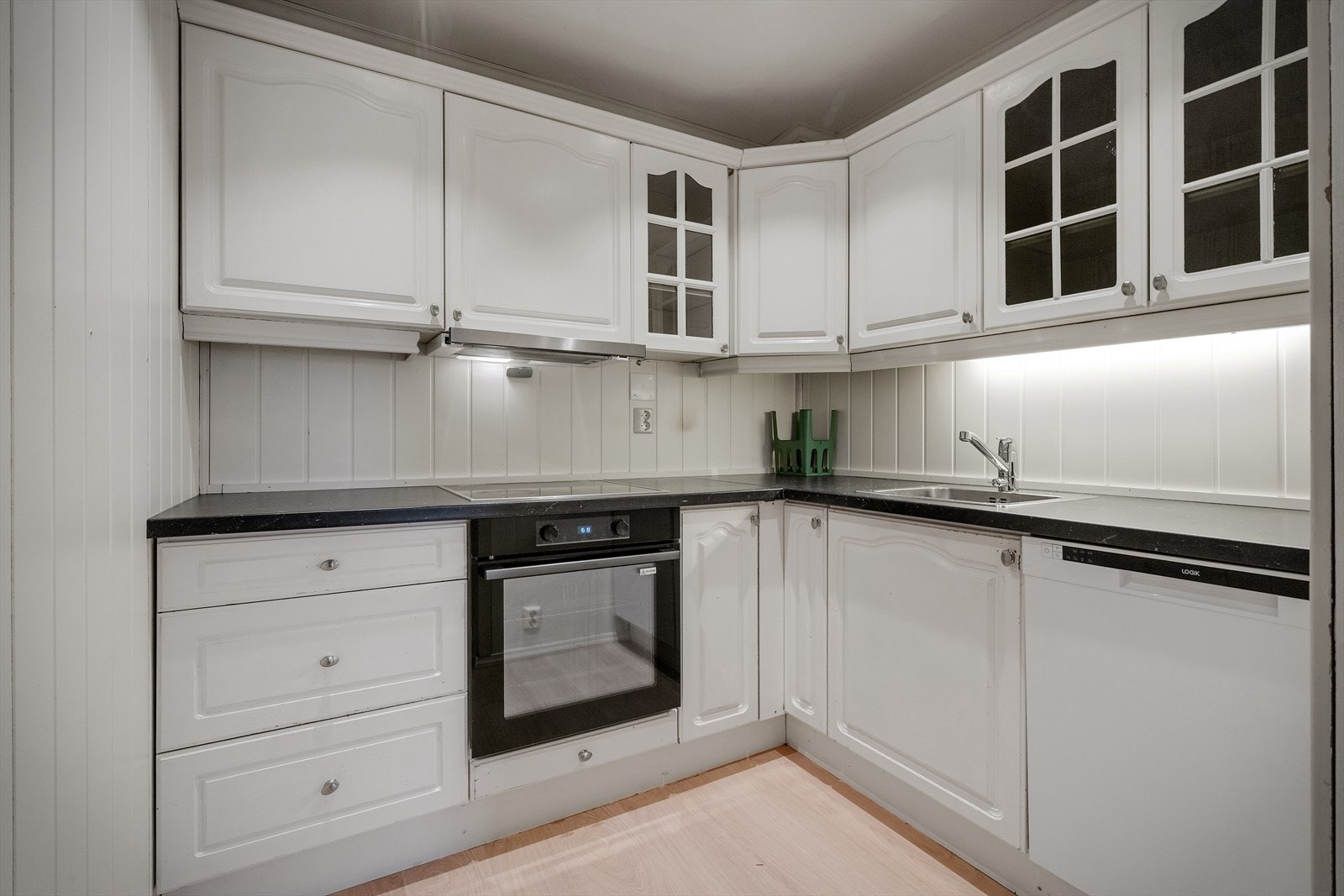 Praktisk kjøkken med god plass til oppbevaring | Kjøkkenet er utstyrt med nedfelt vask, stekeovn, platetopp, oppvaskmaskin og kjøleskap, og har god skap- og benkeplass i en effektiv L-løsning Galleribilde