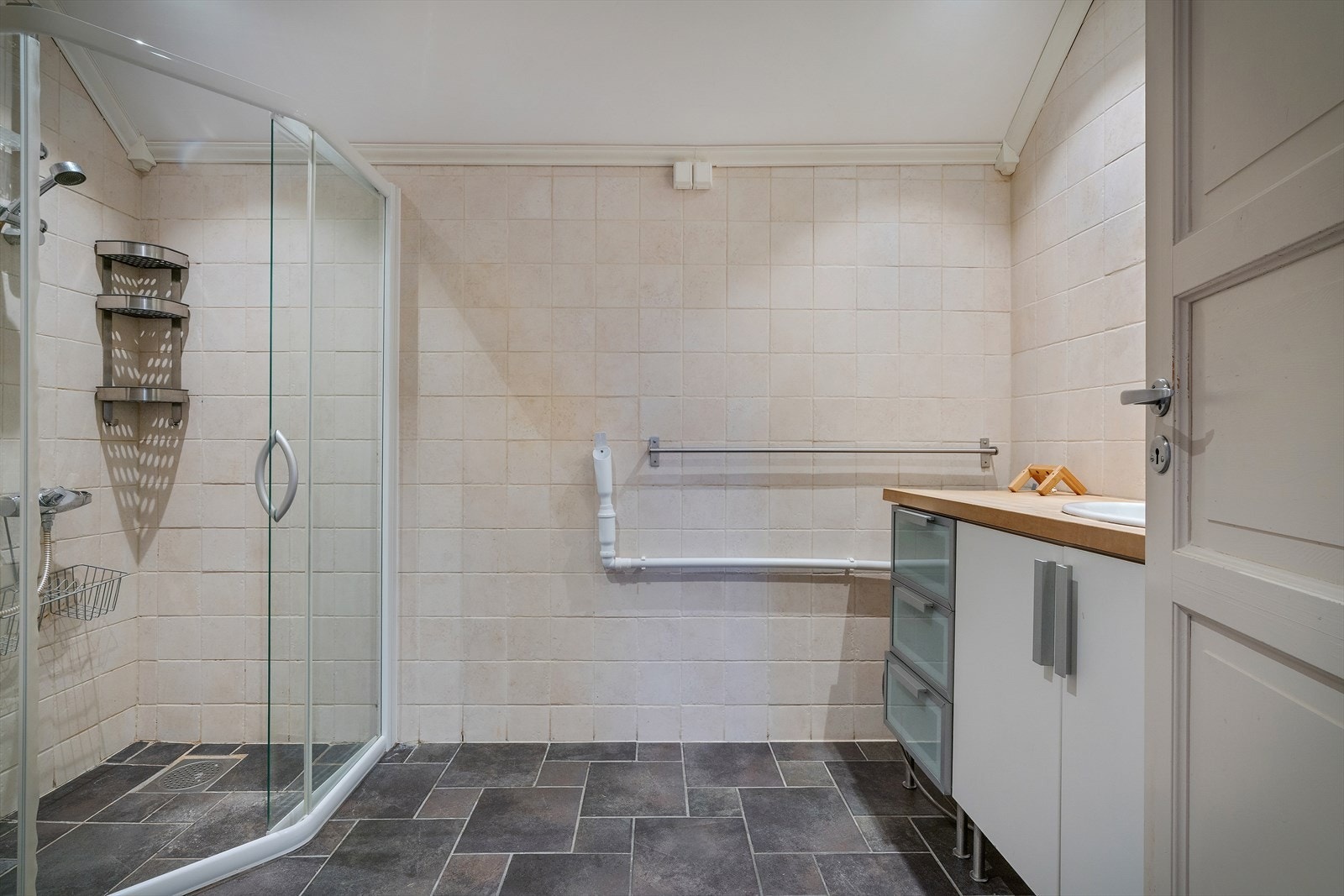 Romslig og funksjonelt baderom med flislagte overflater, opplegg for vaskemaskin og varme i gulv Galleribilde