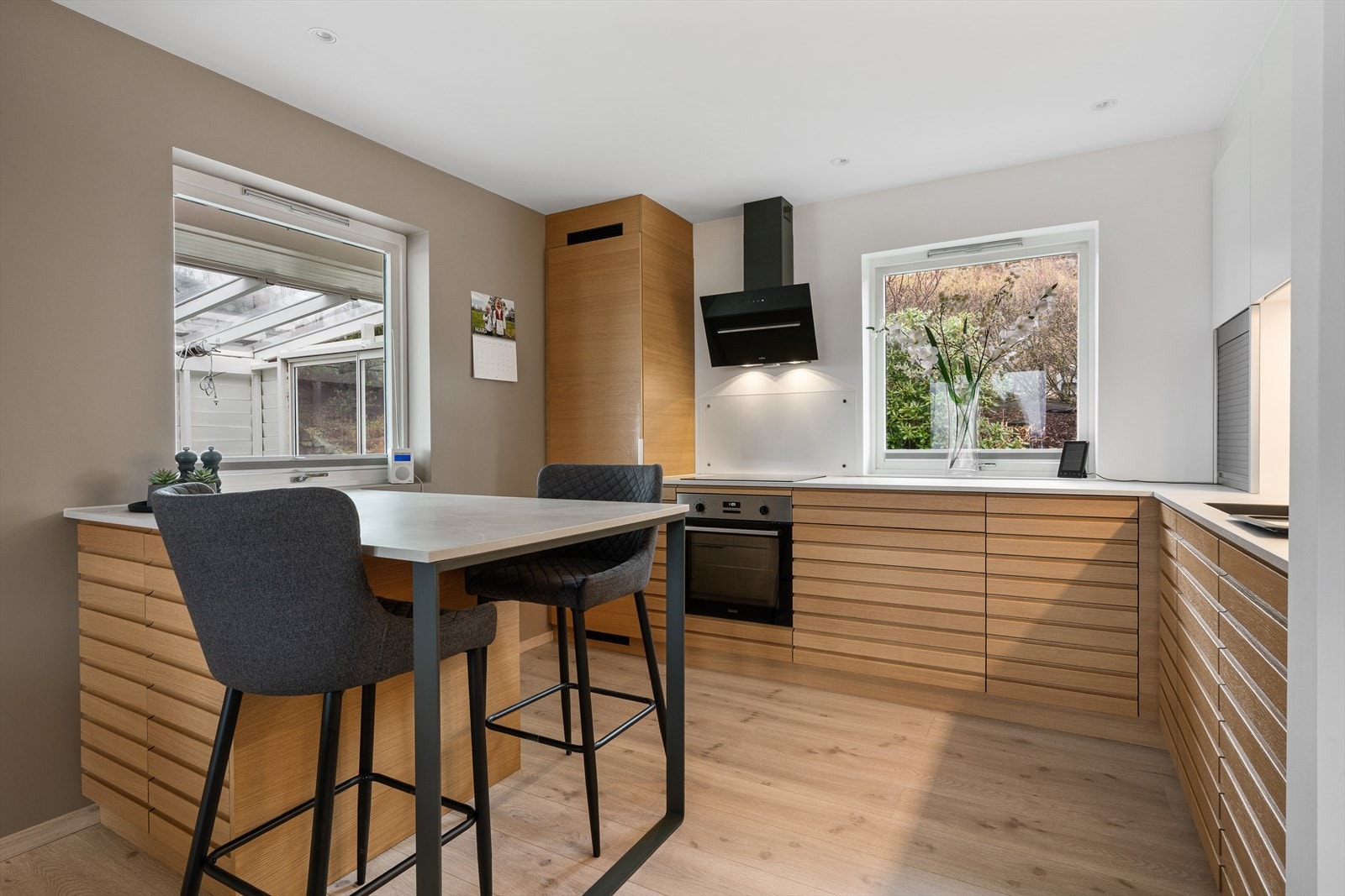 Innredningen har profilerte fronter i varme tretoner kombinert med lyse overskap og benkeplate - et tidløst uttrykk og gode kontraster Galleribilde