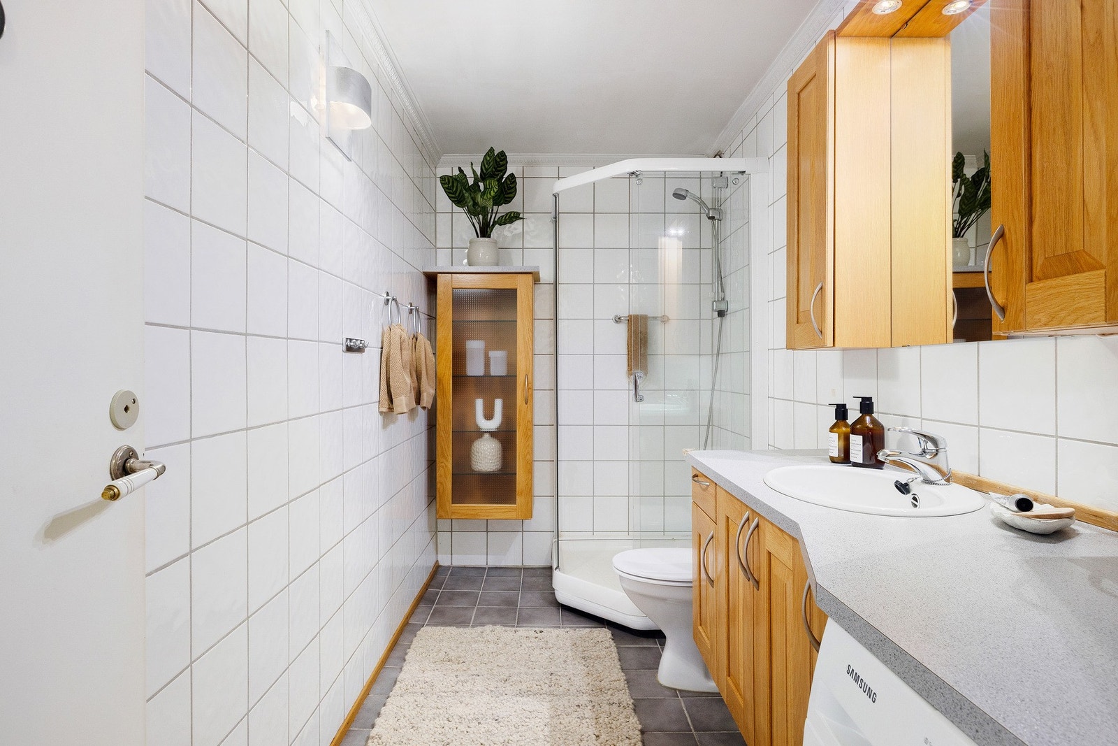 Boligens bad har inngang fra entréen. Lyst, flislagt bad med gulvvarme. Det er opplegg for vaskemaskin. Vaskemaskinen blir stående. Galleribilde