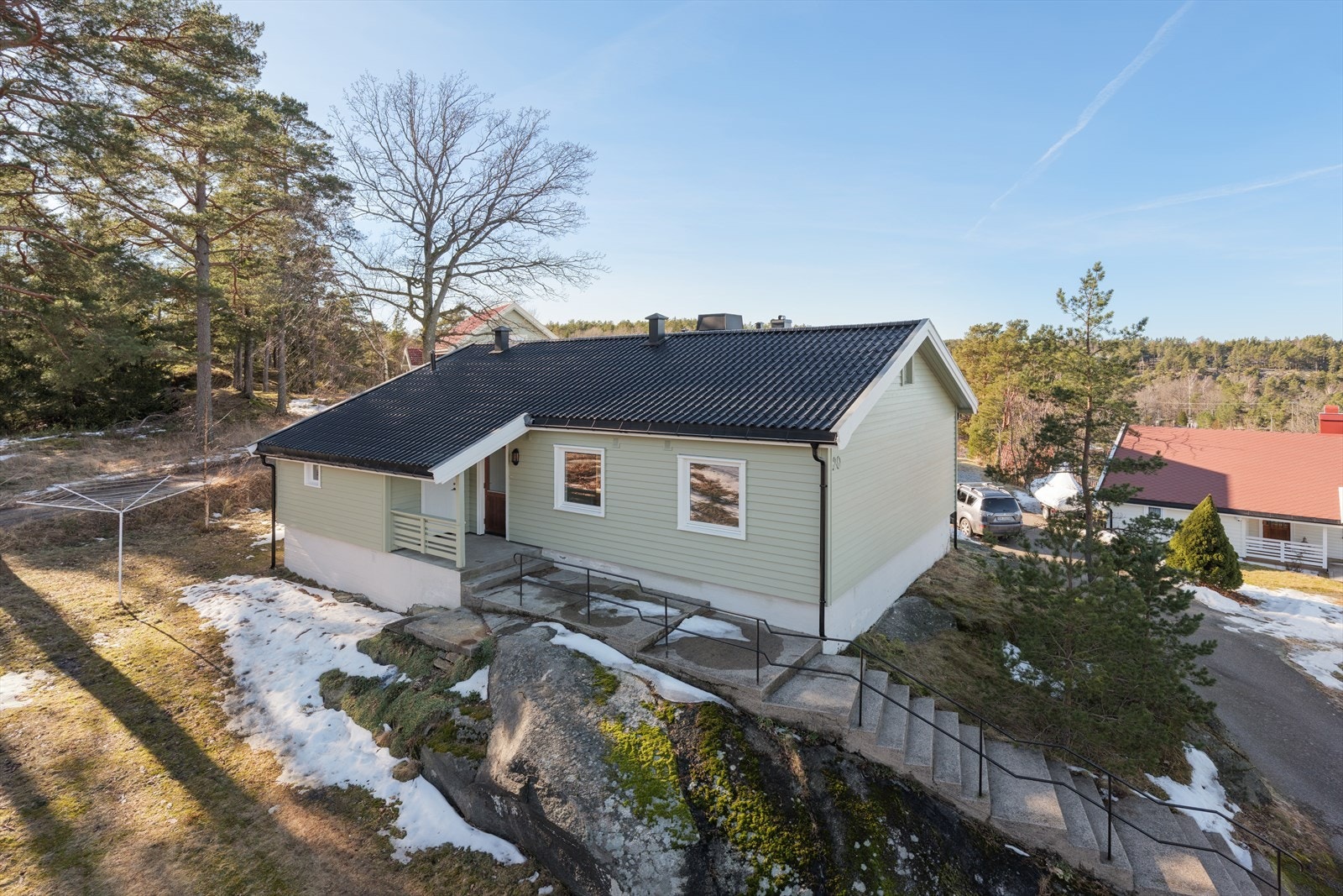 Tomten ligger høyt og fritt og er opparbeidet med plen med noe fjell i terrenget på del av tomten. Stor utvendig bod ved inngangspartiet. Galleribilde