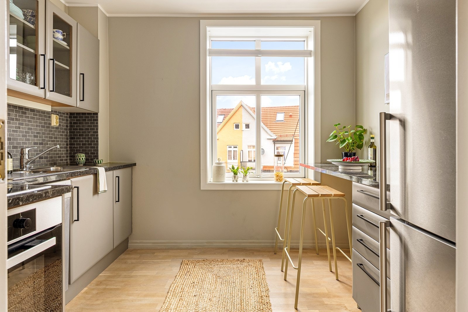 Pen kjøkkeninnredning med slette fronter, ett overskap med glassfront og laminat benkeplate. Galleribilde