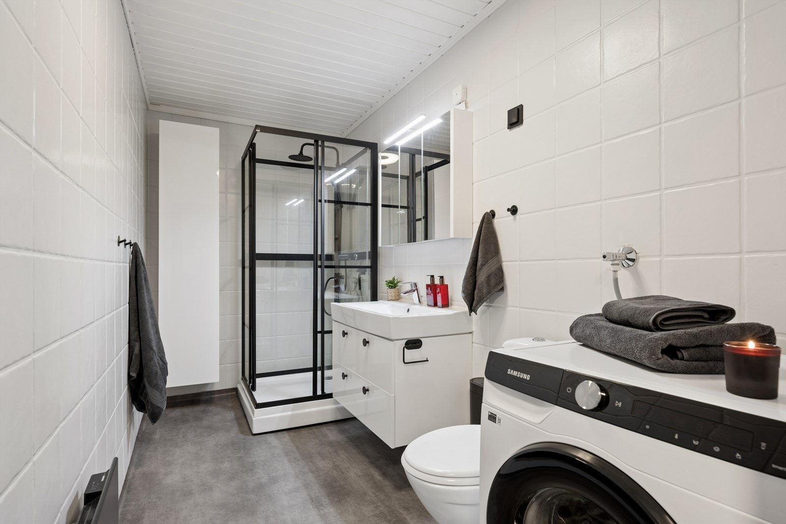 Badet er innredet med en heldekkende servant, overskap med speil, toalett og et dusjkabinett - det er også klargjort med opplegg for vaskemaskin. Galleribilde
