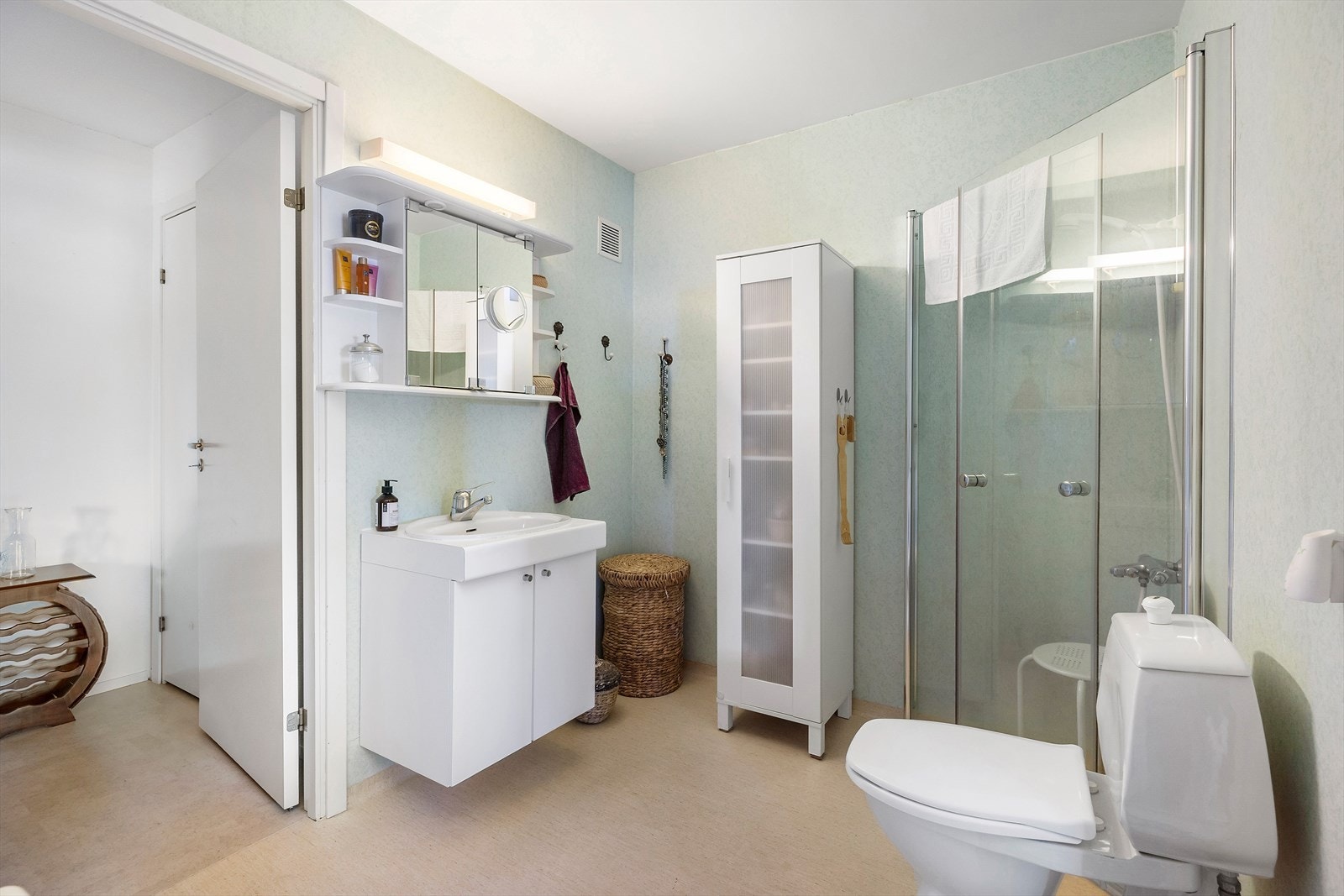 Romslig bad med elektrisk gulvvarme. Badet inneholder dusjhjørne, servant med skapseksjon, speilskap og toalett. Galleribilde