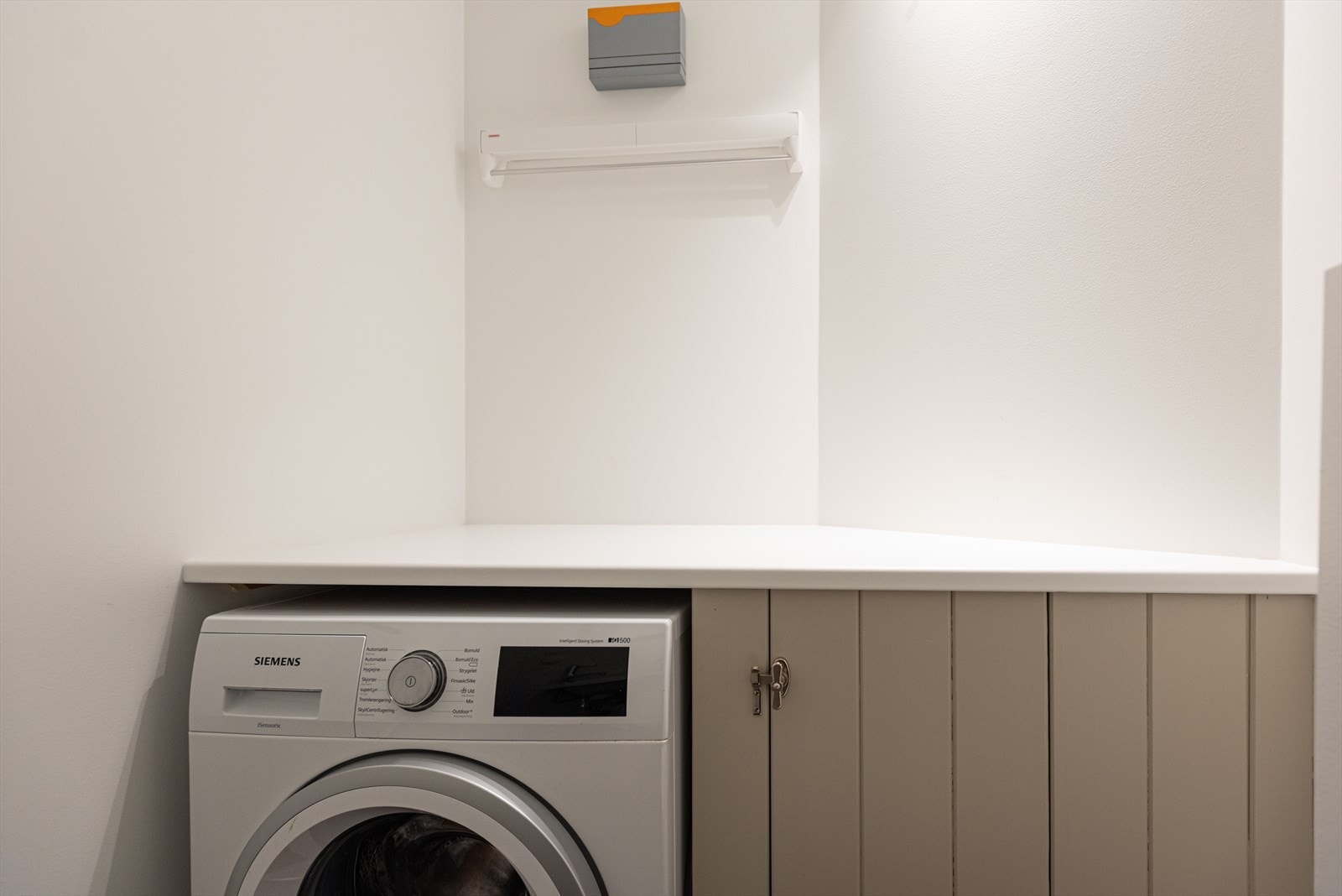 Toalettrommet har flislagt gulv med varmekabler, baderomsinnredning med laminat benkeplate, benkeskap med profilerte fronter og servant, samt vegghengt klosett med innebygget sisterne - Det er opplegg for vaskemaskin og sluk i gulvet Galleribilde