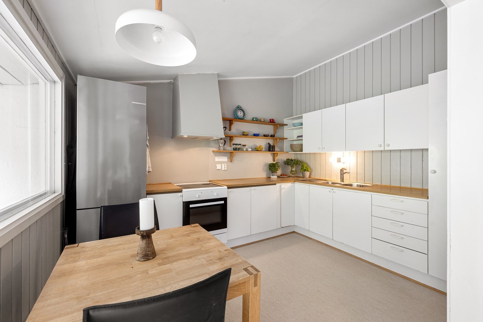 Pen kjøkkeninnredning med lyse, glatte fronter og benkeplate i tre. Godt med både skap- og benkeplass Galleribilde
