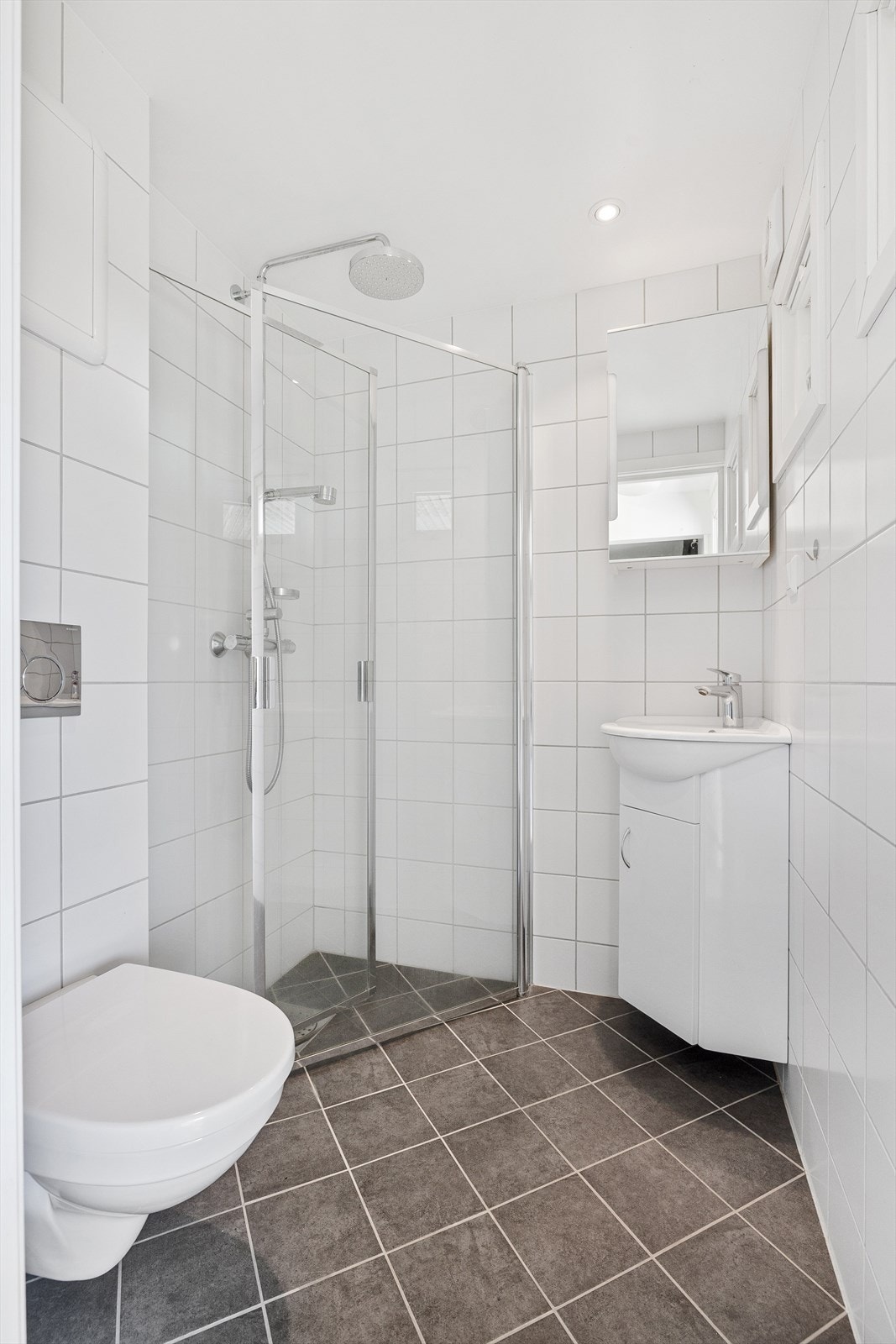 Badet er innredet med servant i innredning med skap, speilskap, dusj og toalett Galleribilde