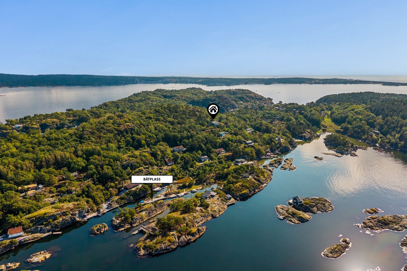 Oversiktsbilde som viser hyttas plassering og den lune båthavna nednefor. Rett ned for hytta ligger en lagune med en nydelig sandstrand. Galleribilde