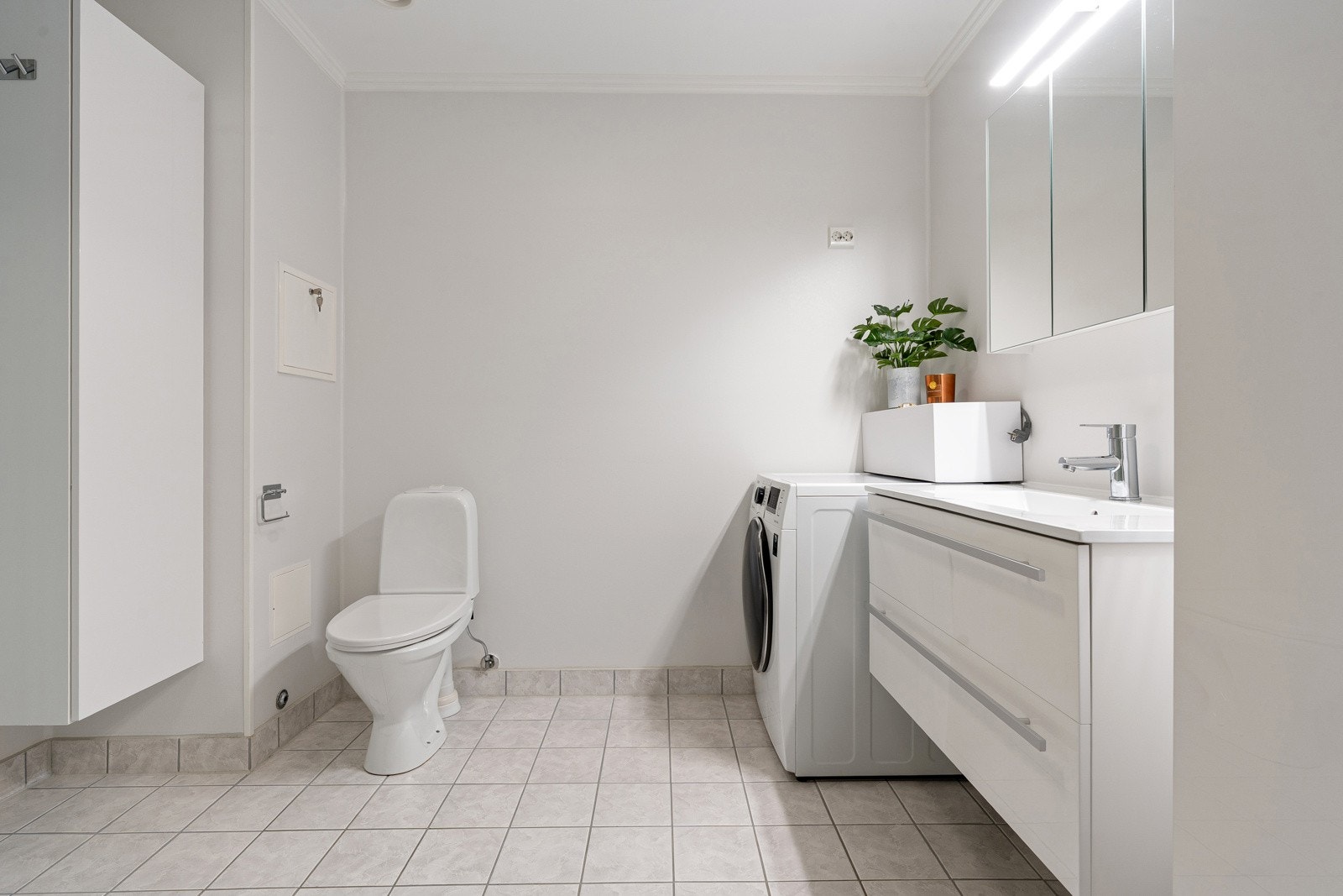 Baderommet er romslig, og utstyrt med wc, dusjkabinett, opplegg for vaskemaskin og baderomsinnredning med mye oppbevaringsplass.