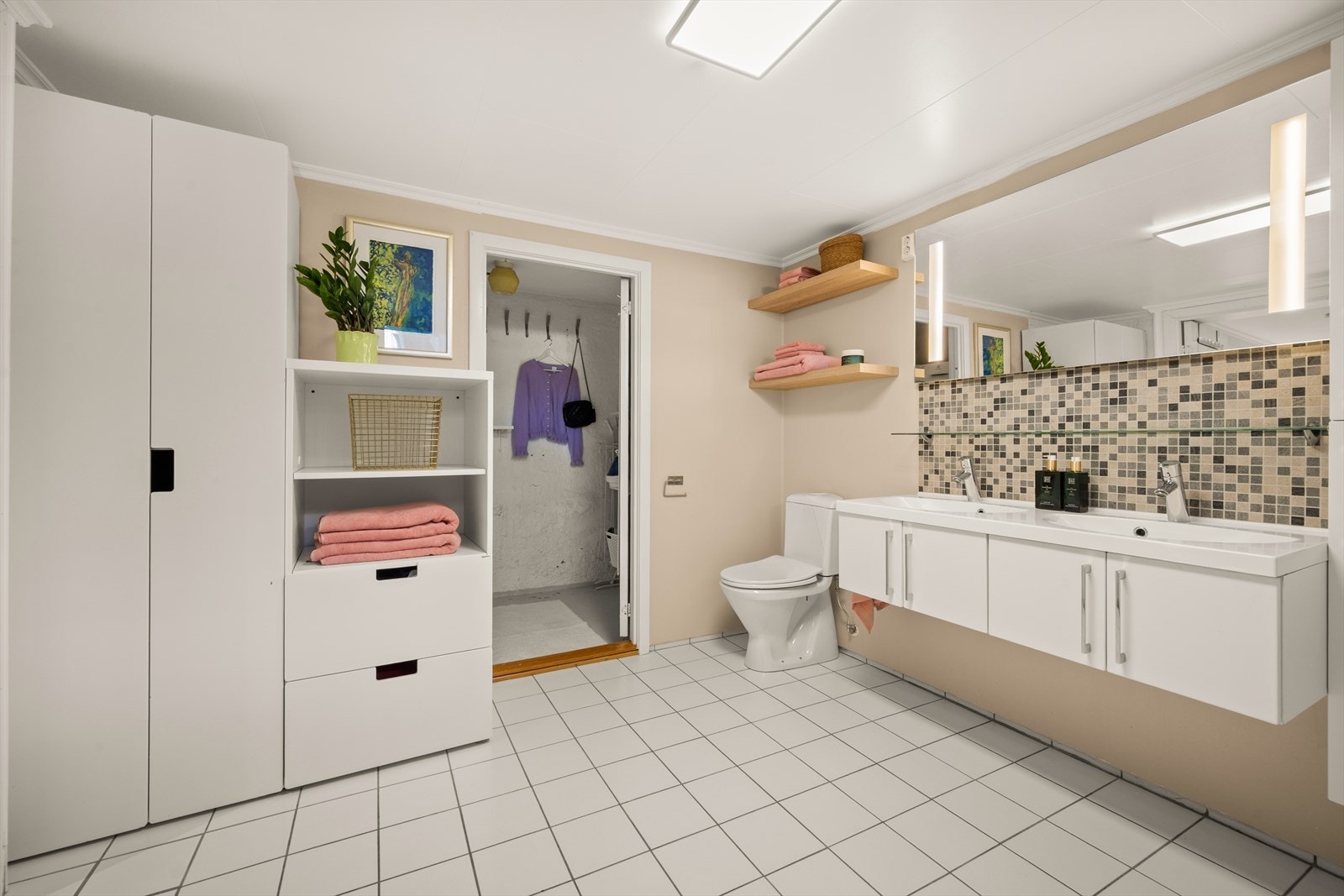 Innredningen består av servantskap og dobbel servant med ettgreps blandebatterier, gulvstående toalett og dusjsone med innfellbare dusjdører. Galleribilde