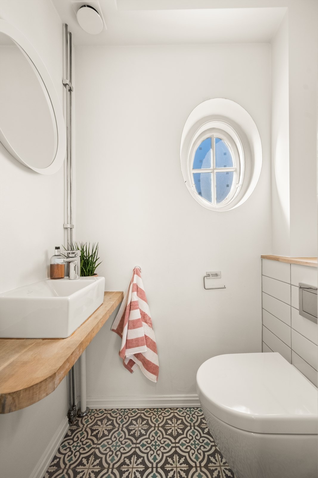 Toalettrom tilknyttet entréen med flislagt gulv, servant og vegghengt toalett. Galleribilde