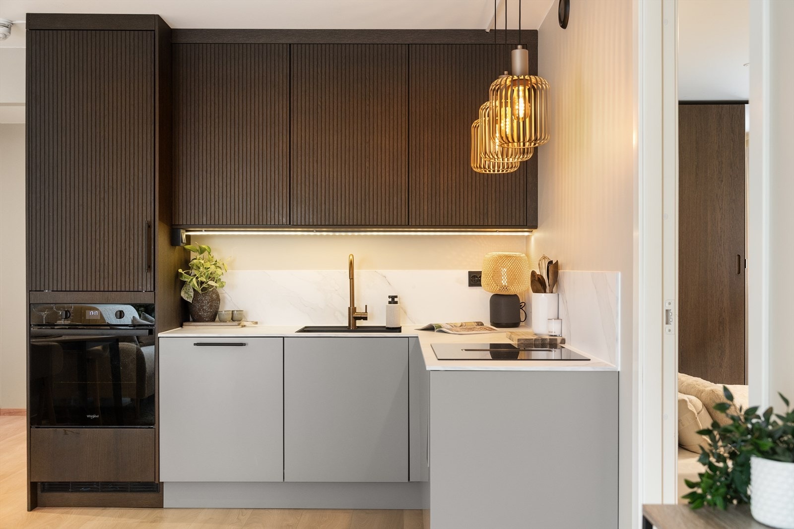 Kjøkkeninnredningen har en kombinasjon av profilerte, mørke fronter i overskapene og slette, lyse fronter i underskapene, som gir et moderne og helhetlig uttrykk. Galleribilde