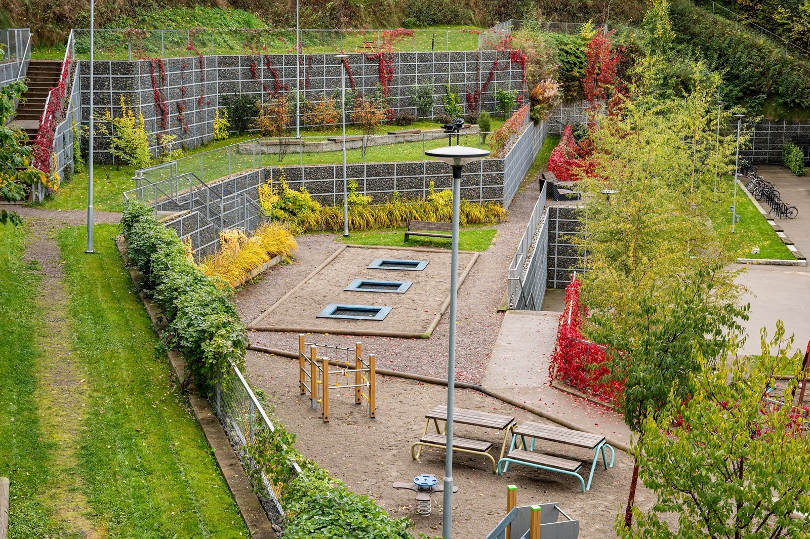 Pent opparbeidet fellesområde med lekestativer, sittegrupper og beplantning. Galleribilde