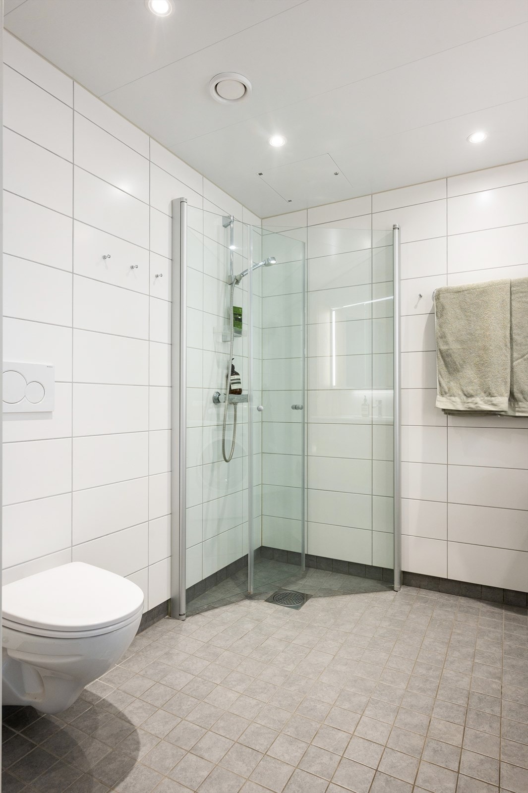 Dusjhjørne med innfellbare dusjvegger, samt vegghengt toalett og opplegg for vaskemaskin. Galleribilde