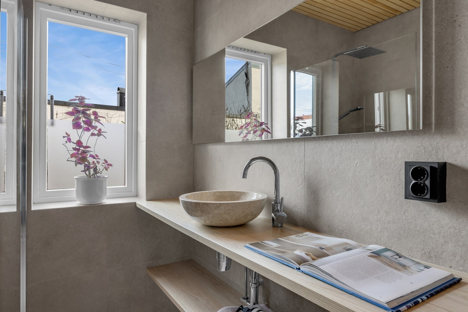 Badet inneholder servant med hyller, veggmontert speil med integrert lys, veggmontert wc, håndkletørker og dusjsone Galleribilde