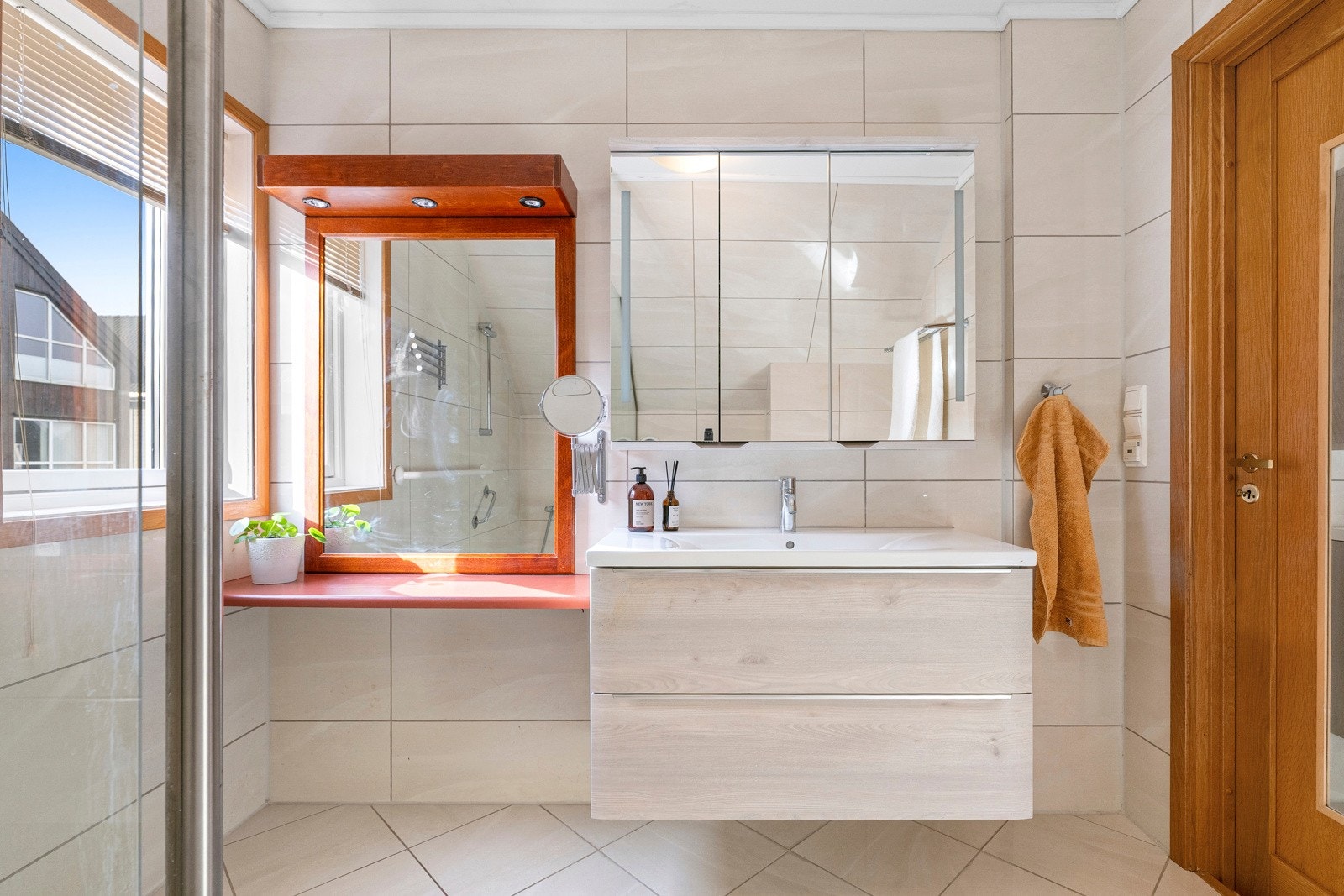 Hovedbadet er romslig og har flislagte gulv og vegger, varmekabler i gulv, dusjnisje, vegghengt toalett og servant med oppbevaringsplass. Galleribilde