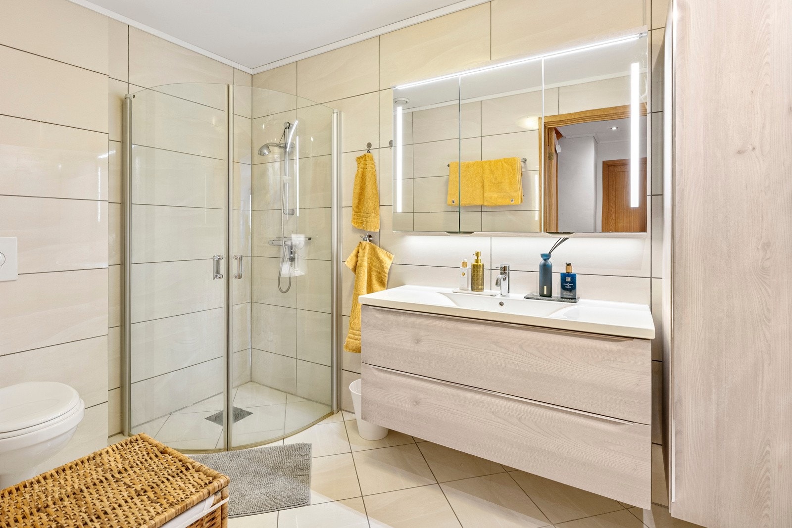 Badet i underetasjen er flislagt og inneholder dusj, vegghengt toalett og servant. Begge badene har varmekabler og belysning integrert i speil. Galleribilde