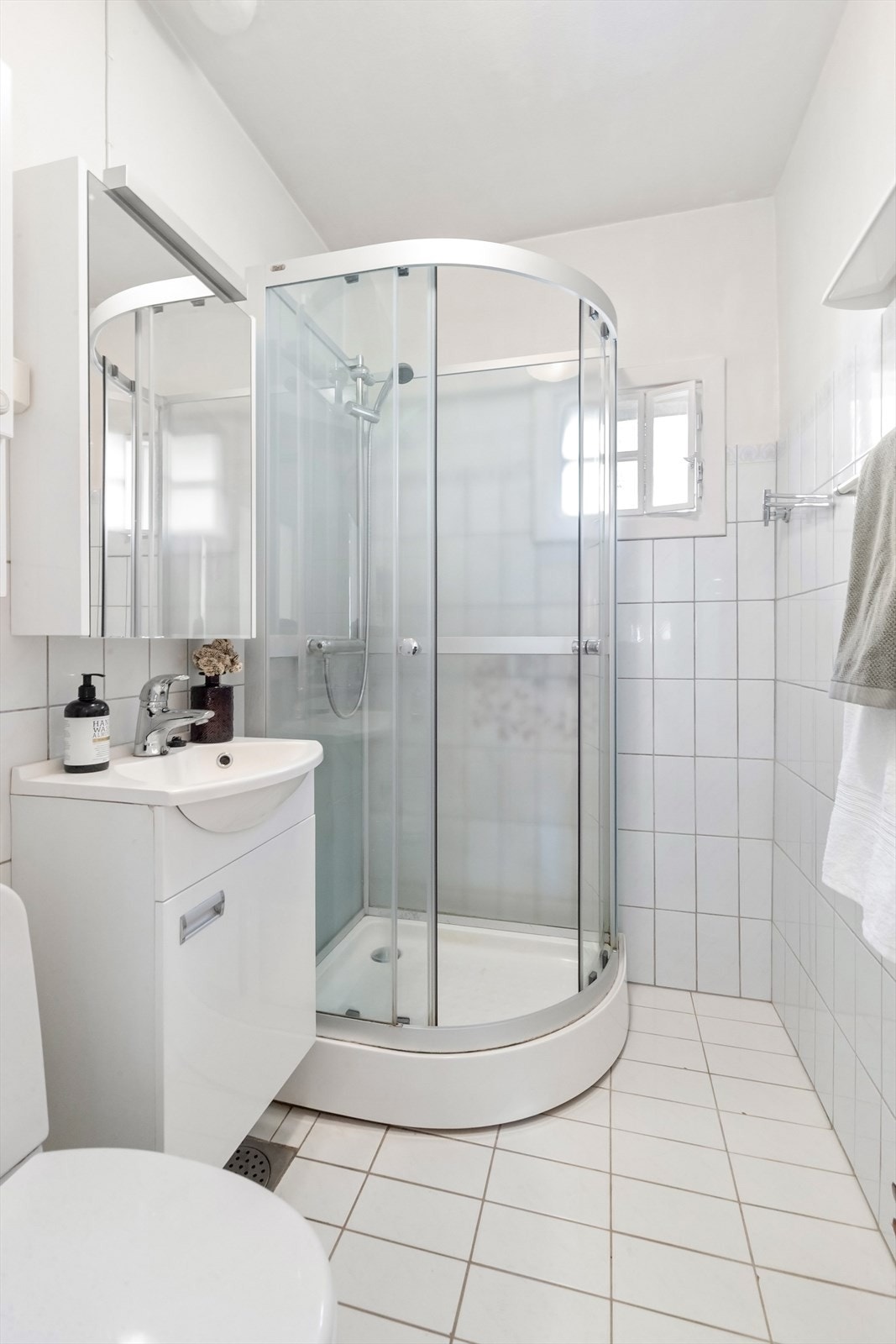 Badet er utstyrt med dusjkabinett, servantinnredning og varme i det flislagte gulvet. Galleribilde