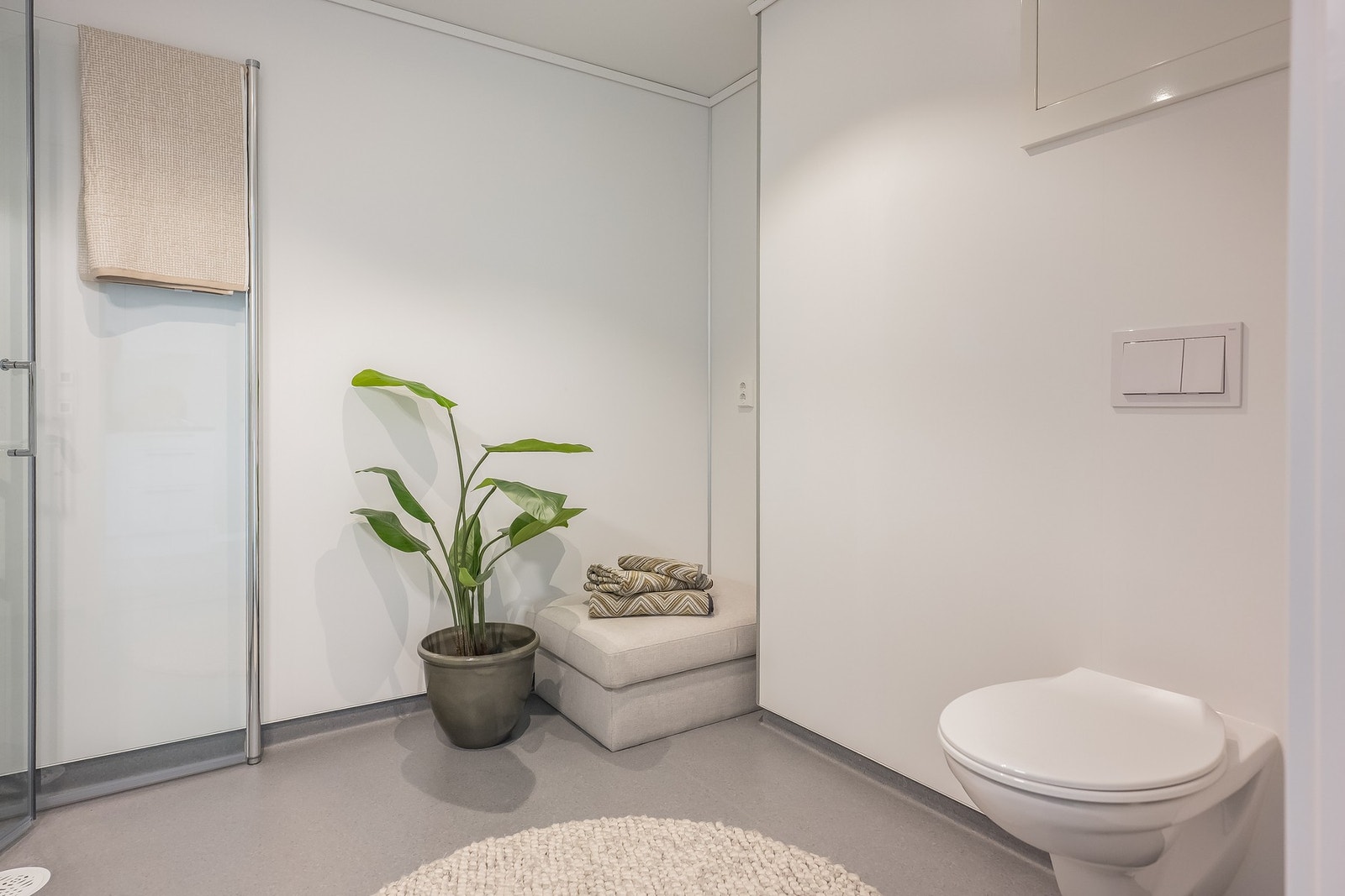 Innskyvbare glassvegger i dusjnisje, vegghengt wc og opplegg for vaskemaskin. Galleribilde