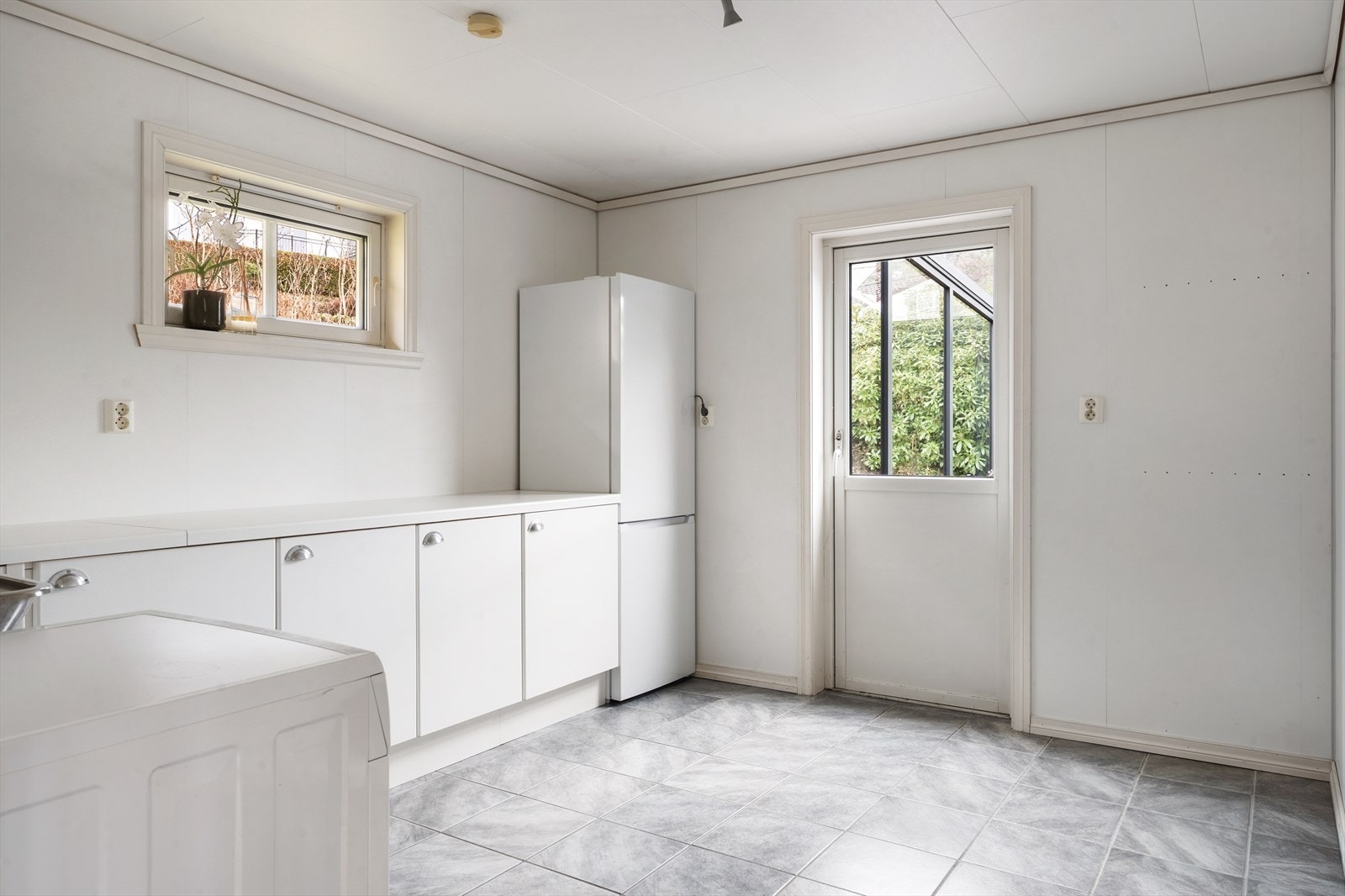 Romslig og praktisk vaskerom med utslagsvask, skapinnredning, samt opplegg til vaskemaskin - I tillegg utgangsdør til terrasse og hage Galleribilde