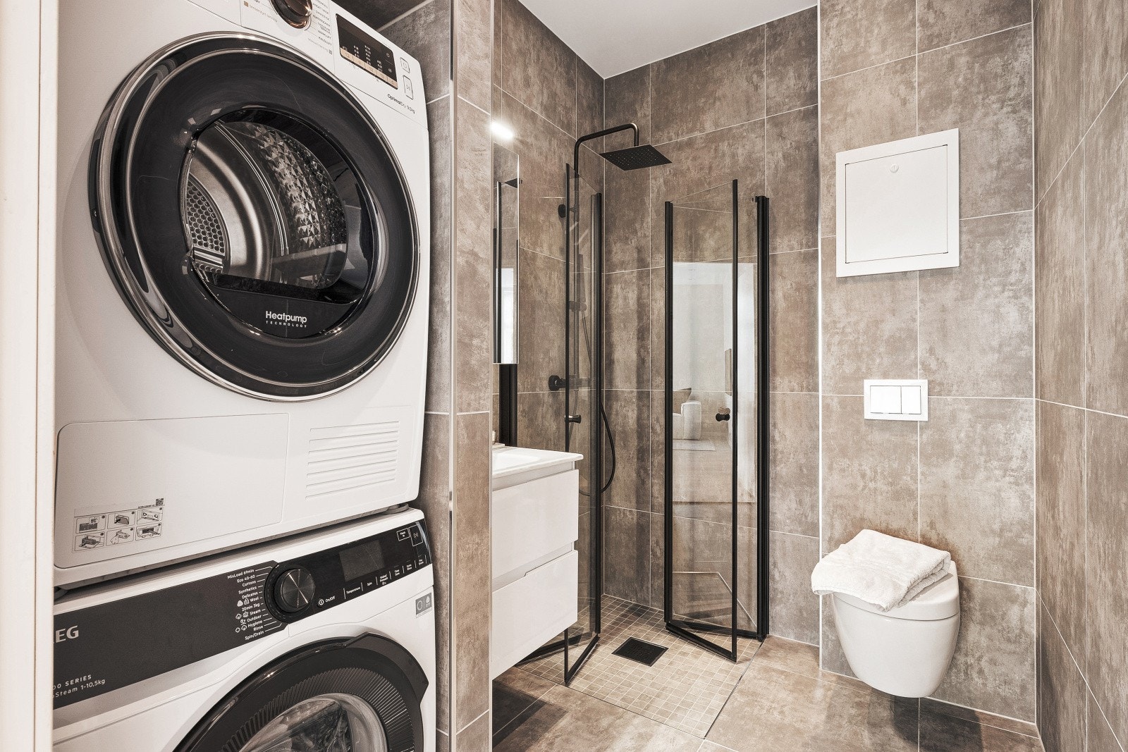 - Badet er innredet med vegghengt toalett, dusjhjørne med glassdører, servant med innredning og opplegg for både vaskemaskin og tørketrommel - Galleribilde