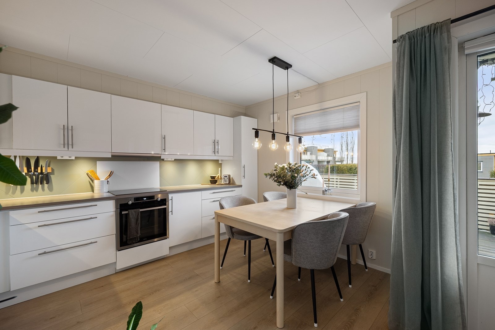 Pent kjøkken med hvit, glatt innredning og laminert benkeplate med nedfelt kum. Galleribilde