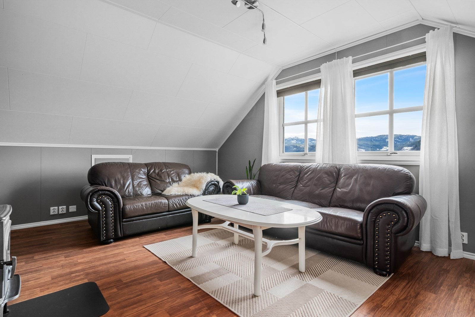 Store sprossevinduer på endeveggen i loftstuen gir fint, naturlig lysinnslipp og langstrakt utsikt. Galleribilde