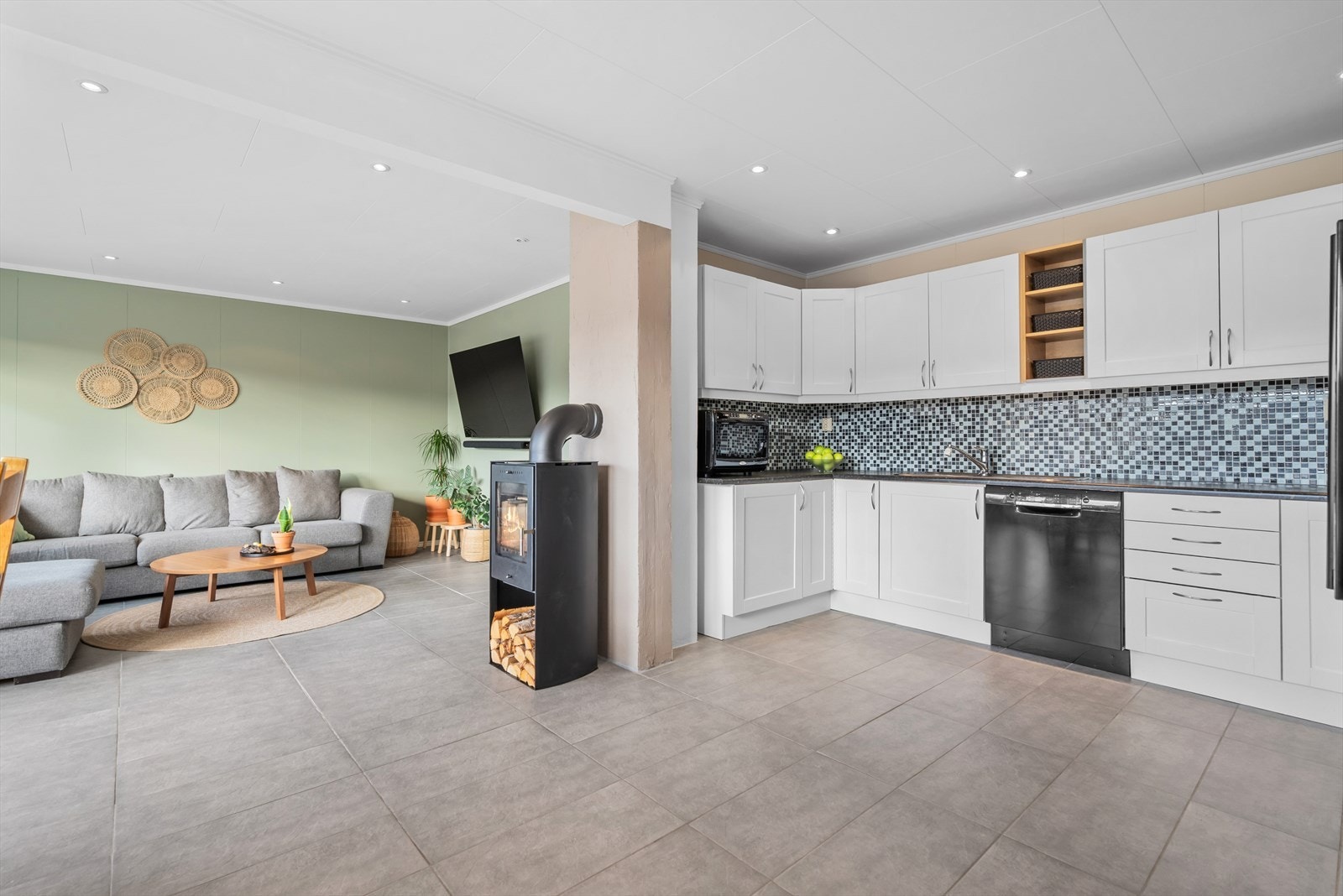 Sentralt plassert mellom stue og kjøkken er det en moderne peisovn. Galleribilde