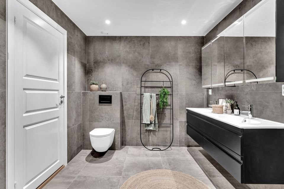Badet er utstyrt med toalett, dobbel servant, dusjhjørnet og med opplegg for vaskemaskin og tørketrommel. Galleribilde