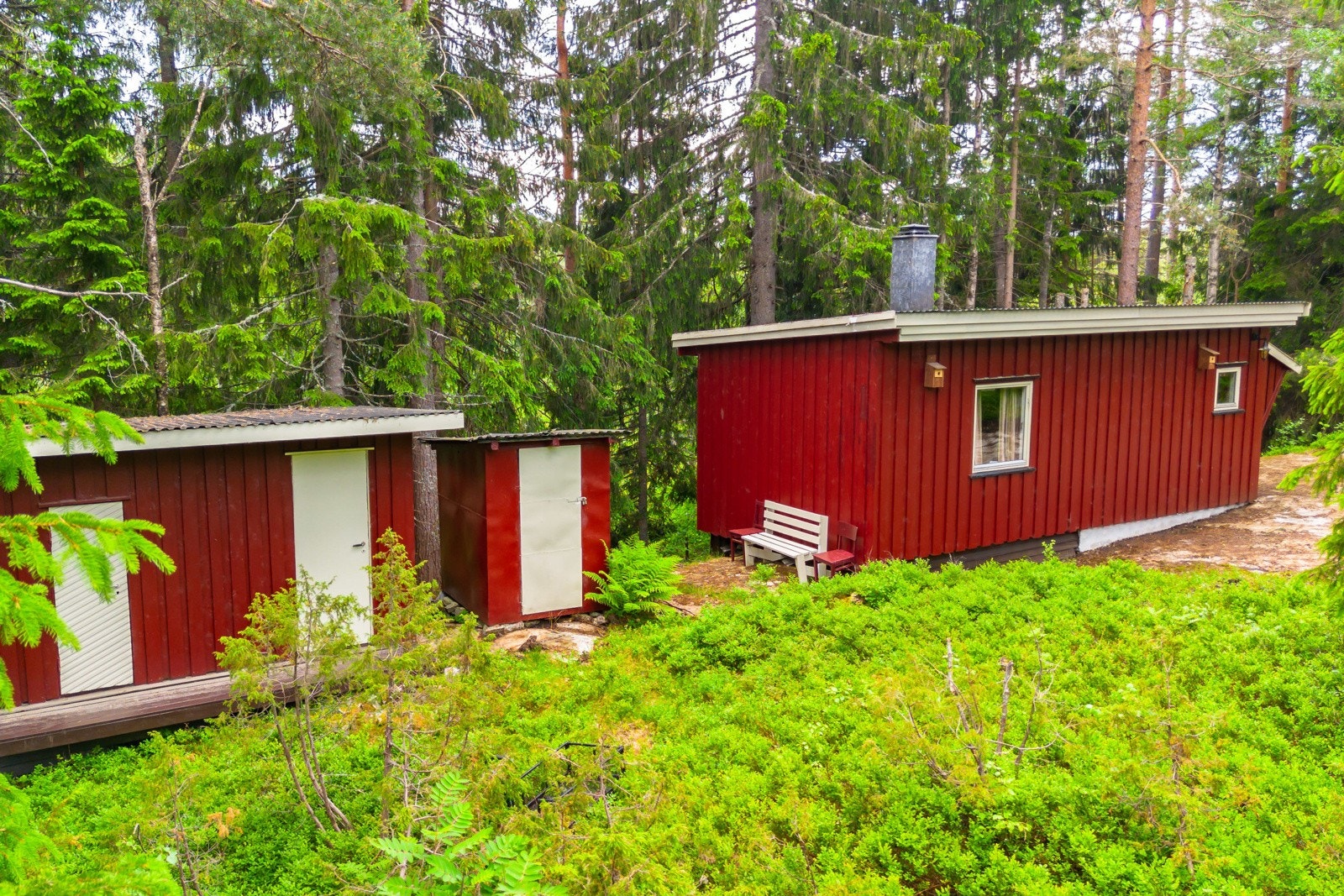 Hytta, et uthus og en utedo ligger på en vakker naturtomt omgitt av trær som gjør det til en skjermet idyll. Galleribilde