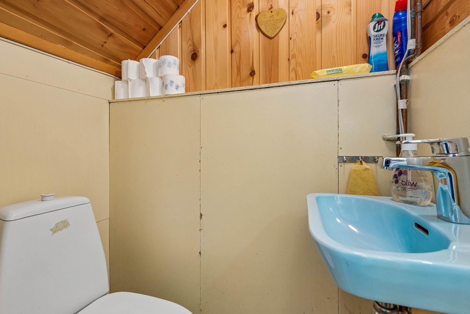 Eget toalettrom i kjeller med belegg på gulv, og vegger med malte plater og trepanel. Montert toalett. servant og avtrekksvifte. Galleribilde