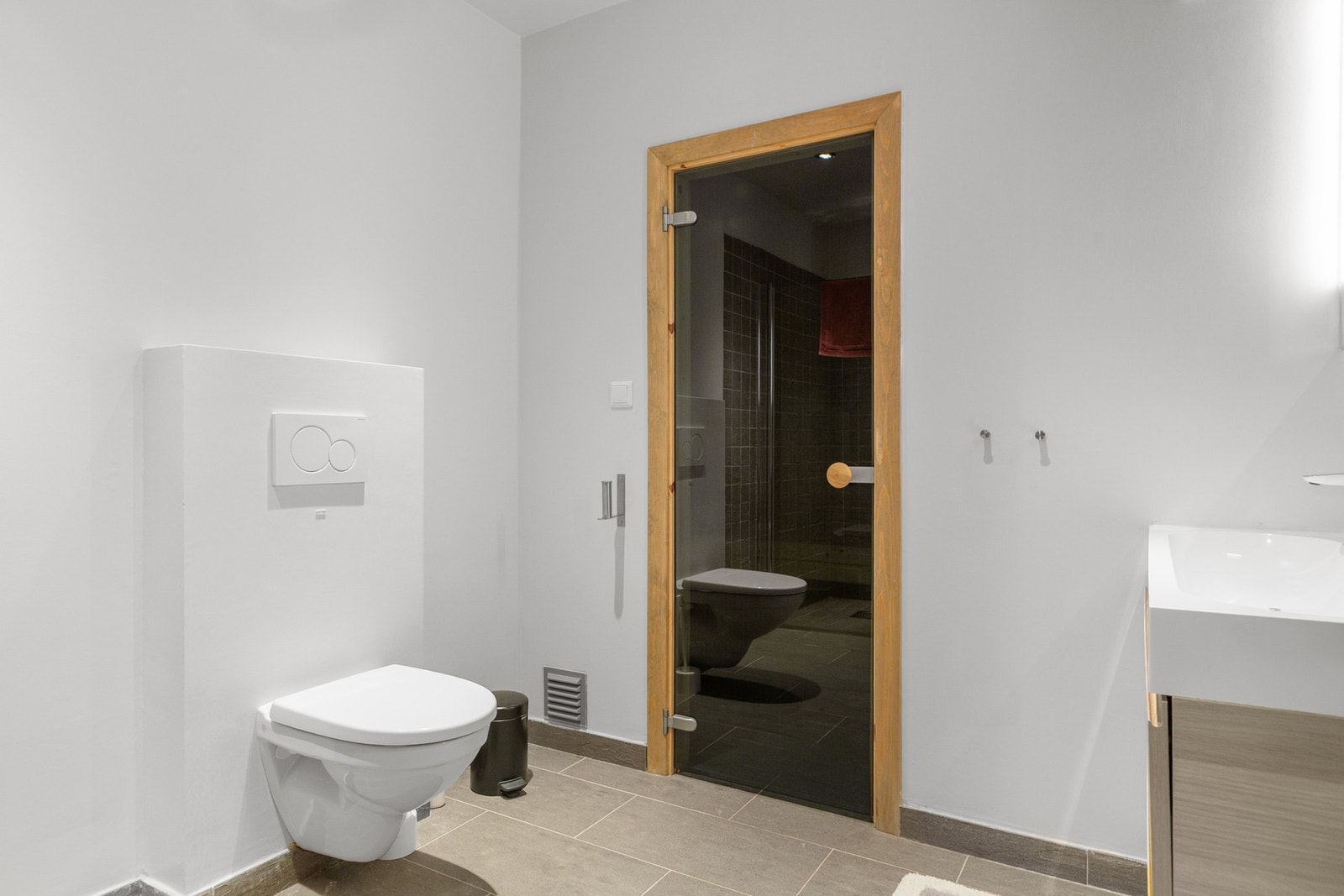 Badet har innredning med nedfelt servant, veggmontert toalett og dusjvegger/nisje. Badestue Galleribilde
