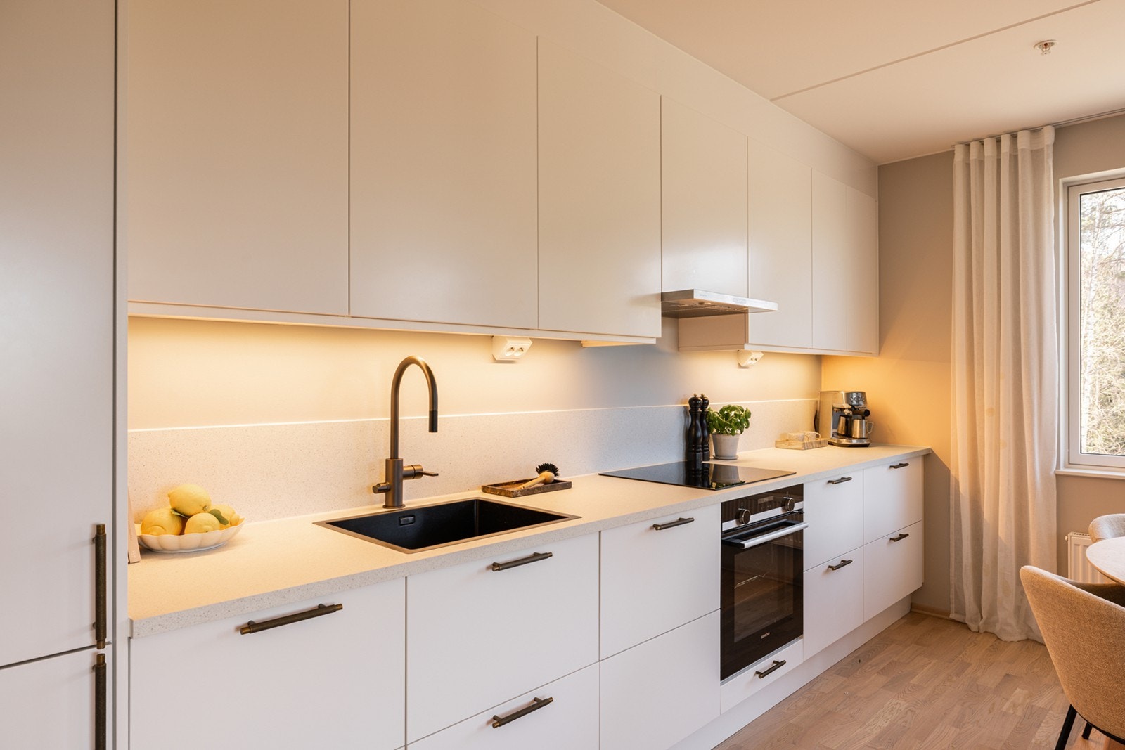 Innredningen består av slette, hvite fronter som gir et stilrent uttrykk, kombinert med laminat benkeplate. Galleribilde