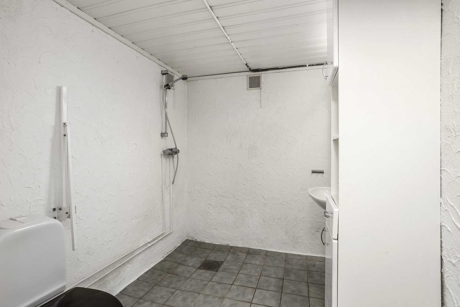 Bad i kjelleren med gulvstående toalett, vask og dusj Galleribilde