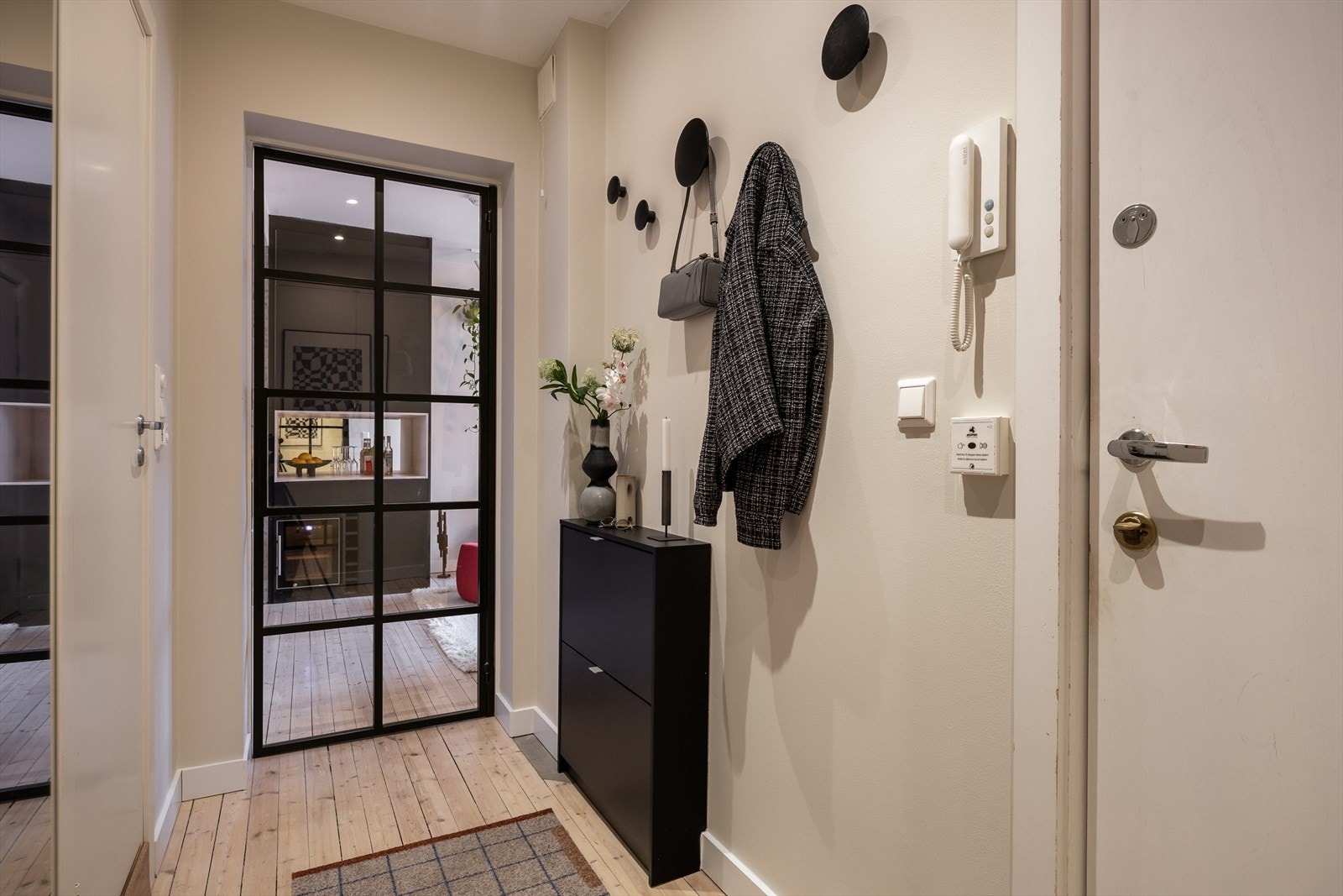 Fra entréen er det direkte adkomst til badet og en elegant smijernsdør skaper en stilfull overgang mellom gang og stue. Galleribilde