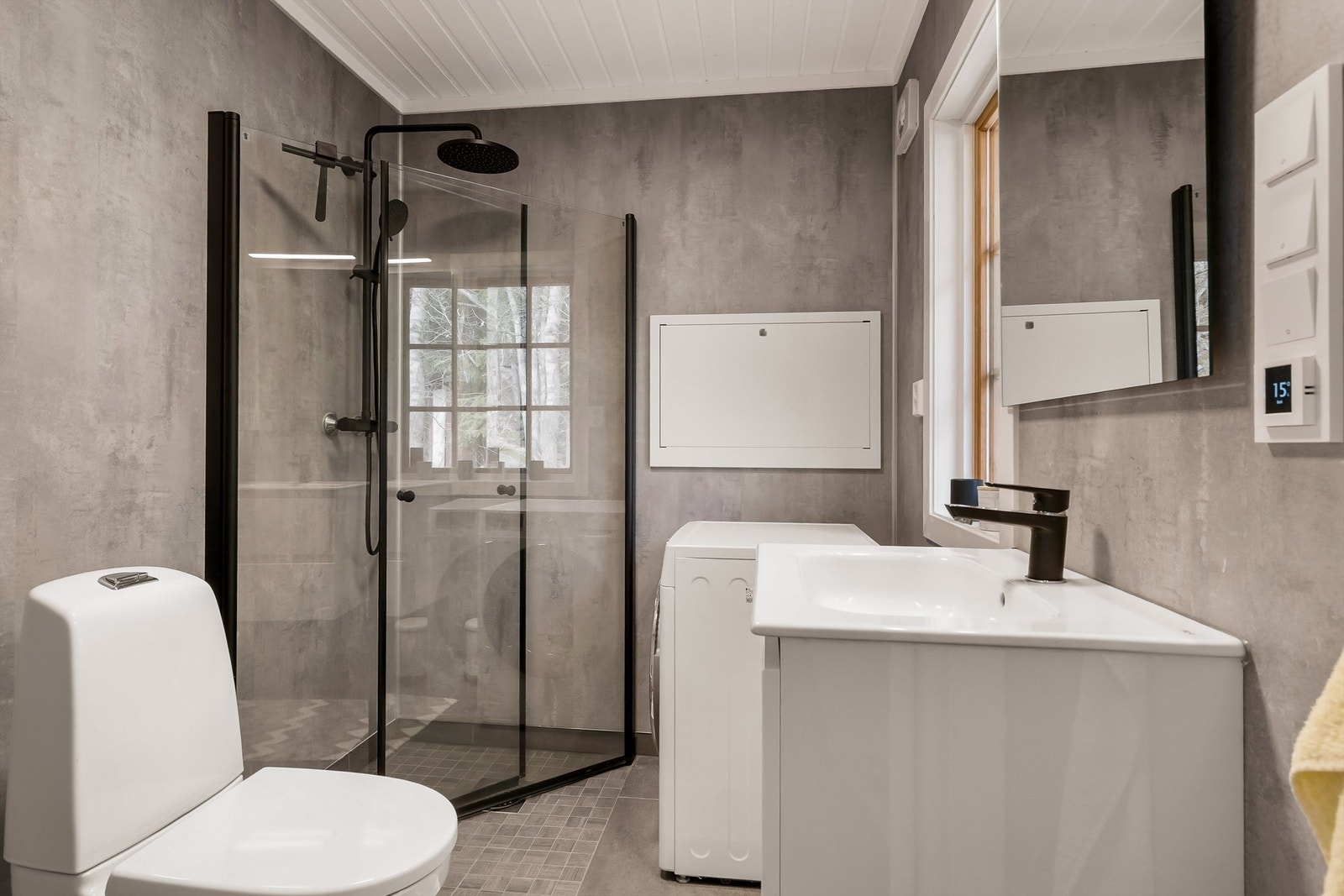 Badet har flislagt gulv og våtromsplater på veggene. Det er utstyrt med dusj, wc, servant i seksjon og vaskemaskin. Galleribilde