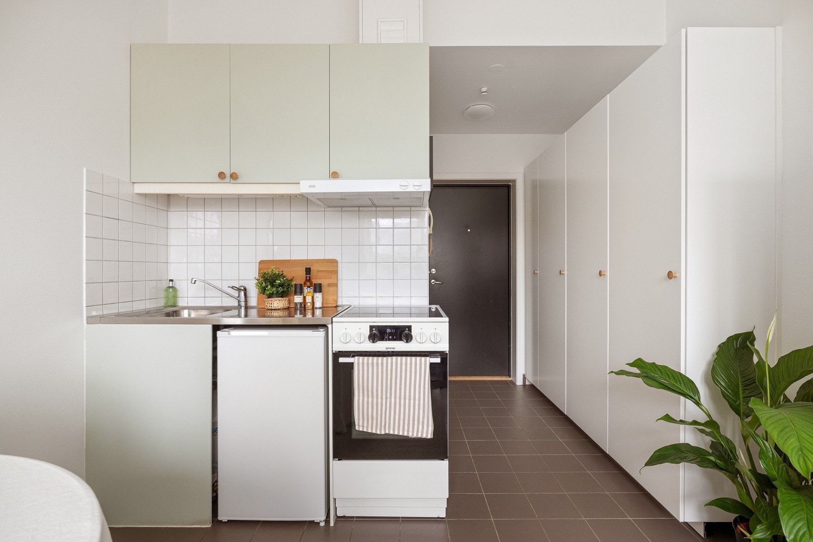 Kjøkkeninnredningen har glatte fronter, samt en benkeplate av rustfritt stål. Det er lagt fliser på veggen mellom benkeplaten og overskapene som sørger for en enklere rengjøring. Galleribilde