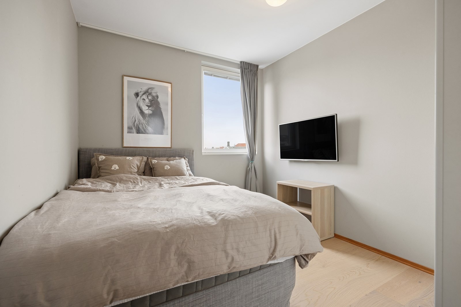 Lyst og innbydende soverom med varme beige vegger, lyst gulv og romslig skyvedørsgarderobe - her er ro og orden i perfekt balanse. Galleribilde