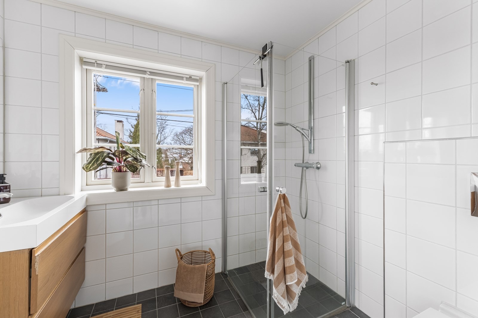 Badet er innredet med dusjhjørne, vegghengt klosett, servantinnredning, varmekabler i gulv og balansert ventilasjon, og fremstår som et funksjonelt og komfortabelt våtrom. Galleribilde