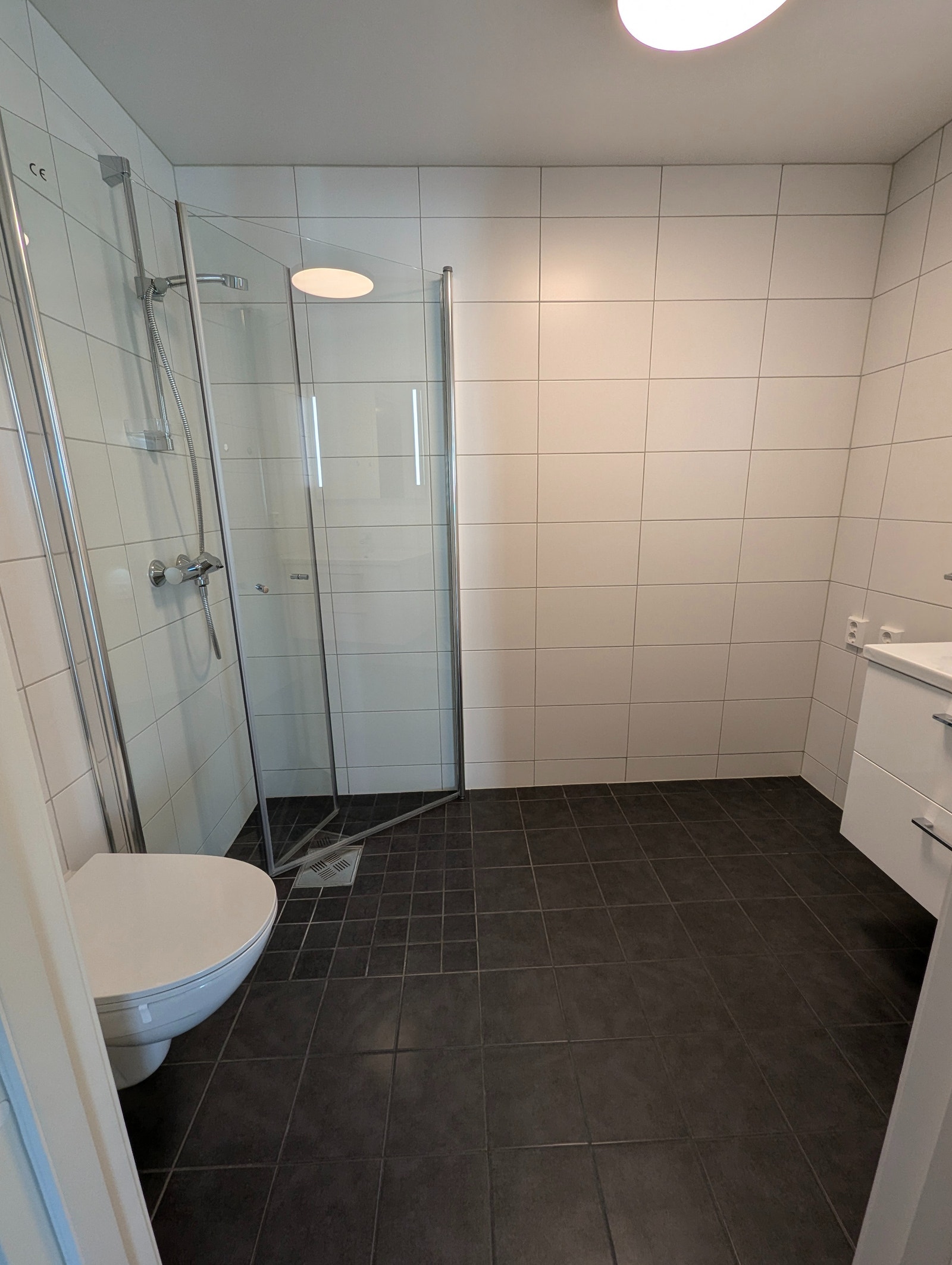 Dusjhjørne med innfellbare glassdører og vegghengt toalett Galleribilde