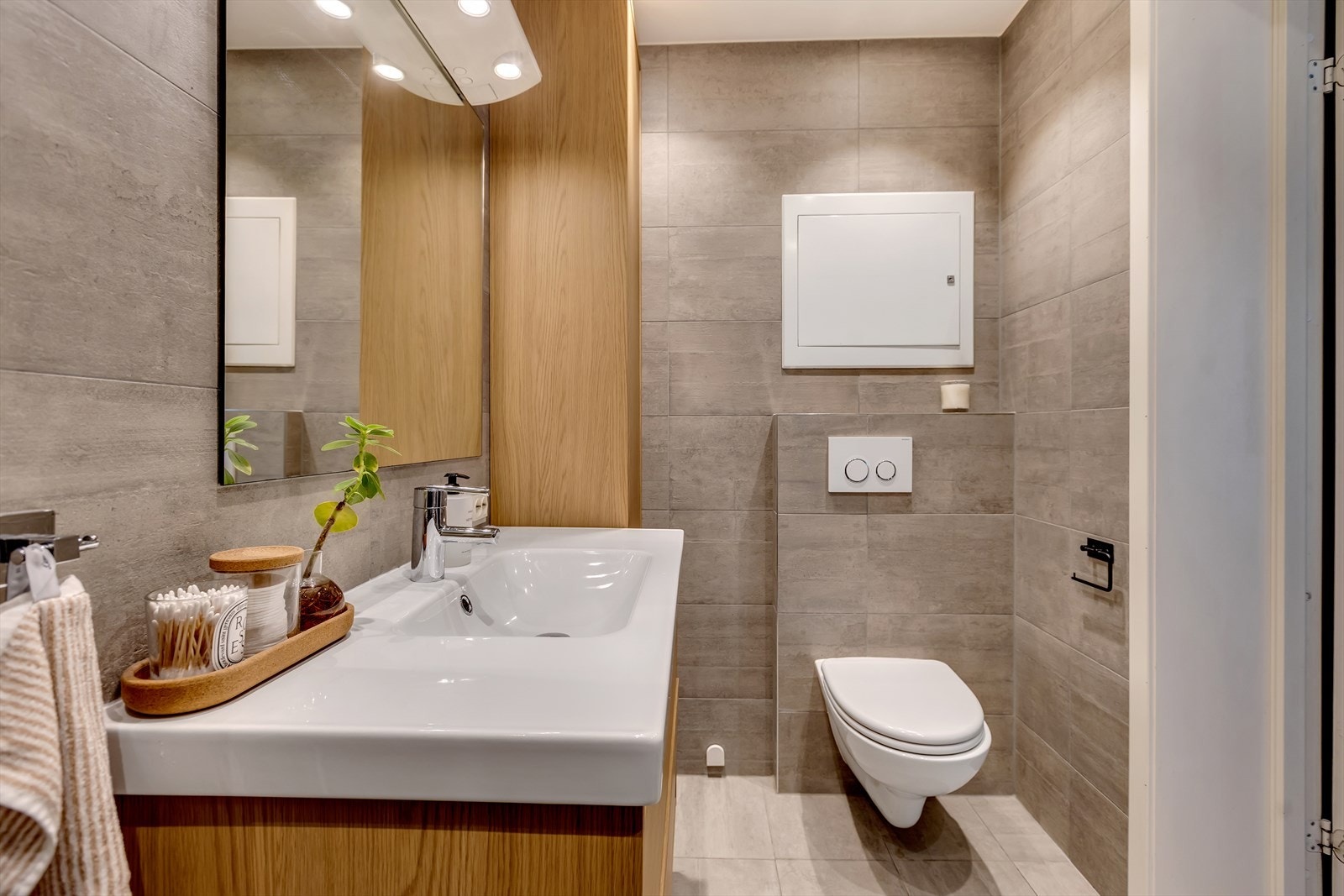 Badet fremstår som pent og funksjonelt, med vegghengt WC, servant i innredning med ettgreps blandebatteri og speil med belysning. Galleribilde