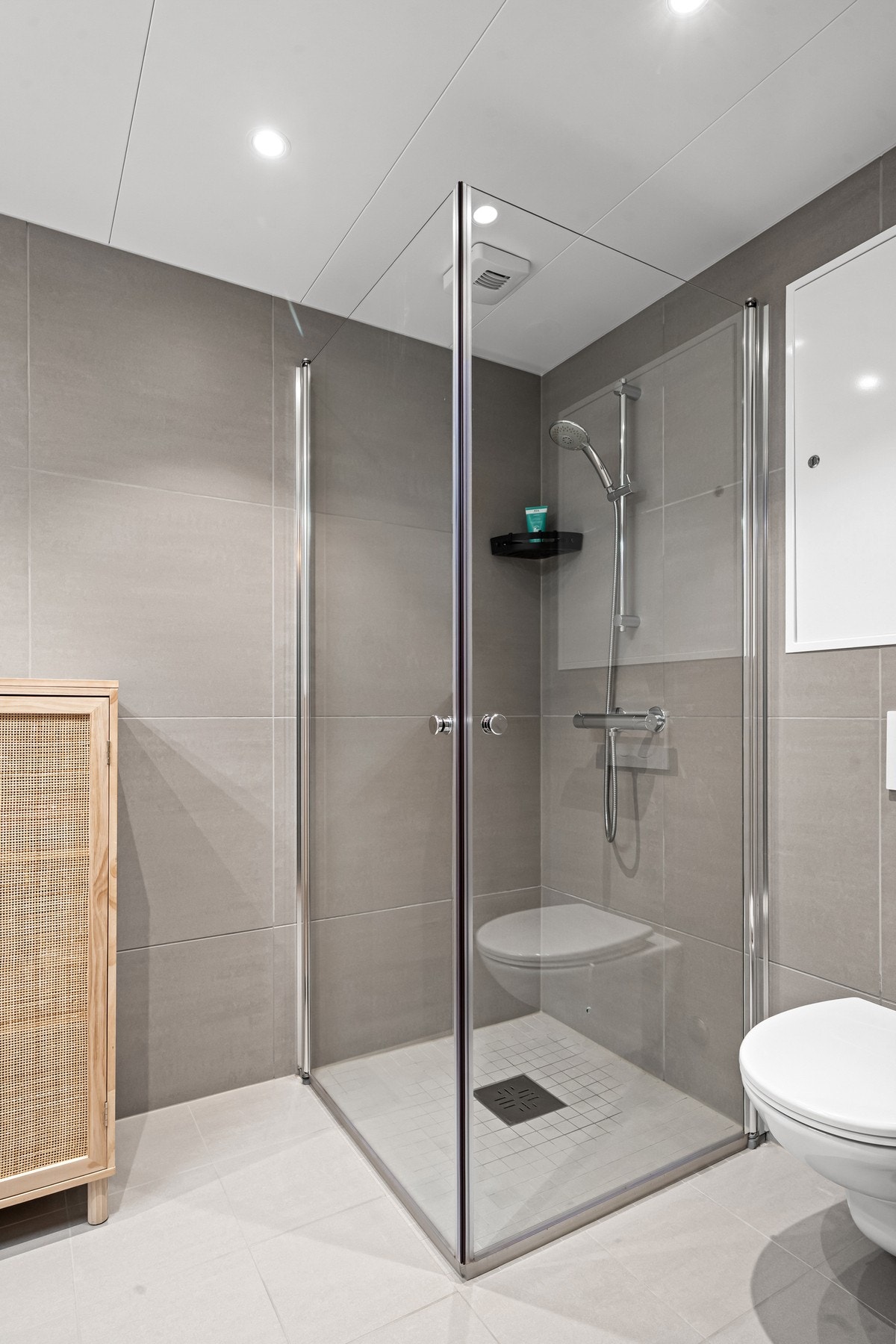 Flott dusjhjørne med foldbare glassdører, mosaikkfliser og sluk i sone Galleribilde