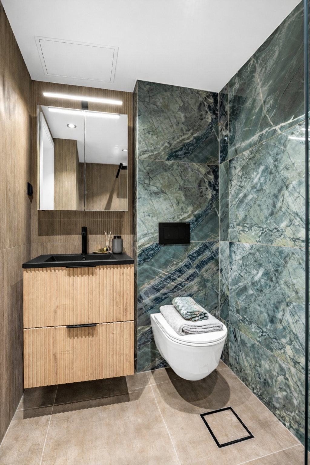 Badet er utstyrt med servant med underskap, speilskap med belysning og veggmontert toalett. Galleribilde