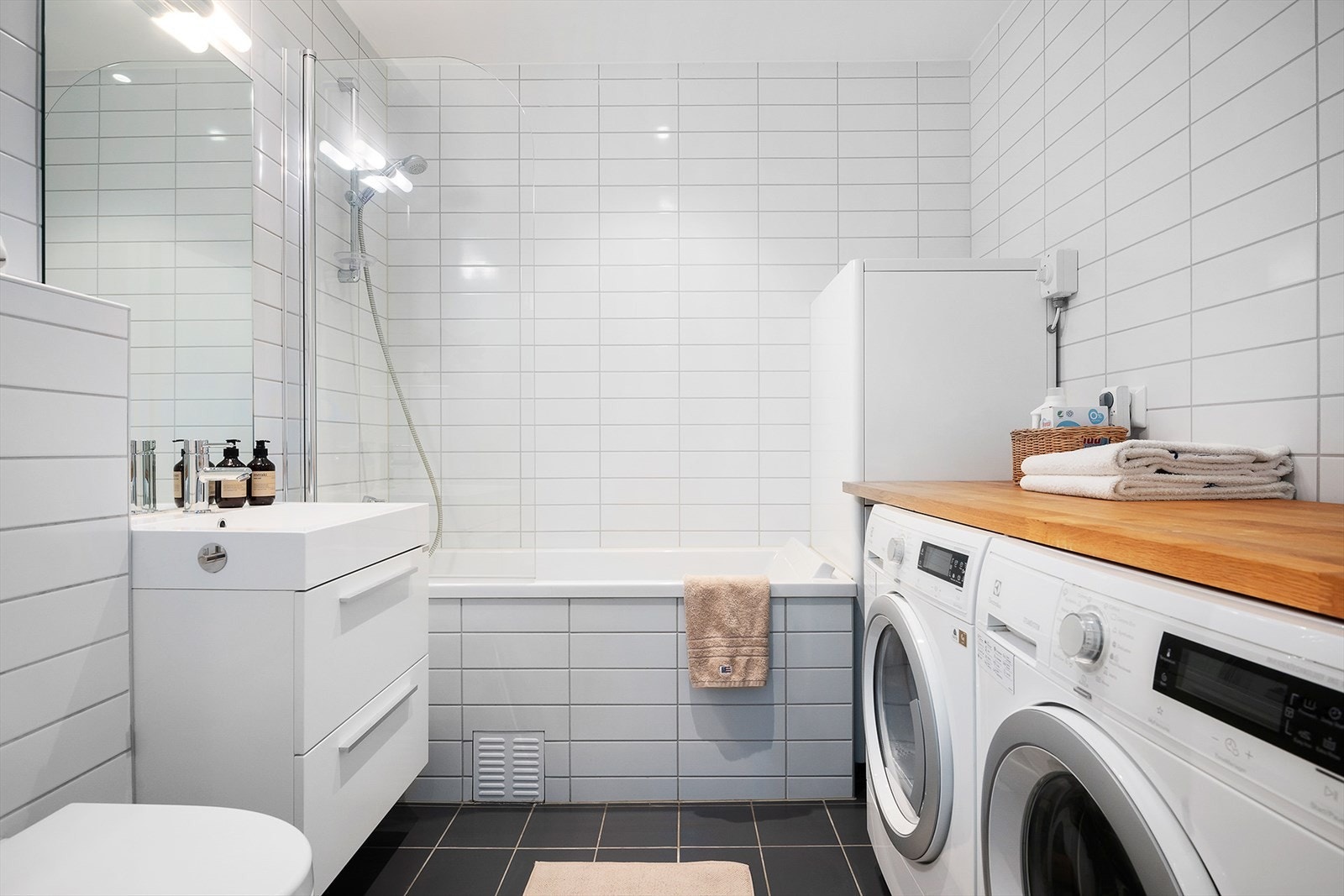 Badet i underetasjen er fra byggeåret og har flislagte overflater. Rommet er innredet med baderomsinnredning med glatte fronter, servant i helstøpt plate, vegghengt toalett og opplegg for vaskemaskin. I tillegg har badet et innbygget og flislagt badekar. Galleribilde