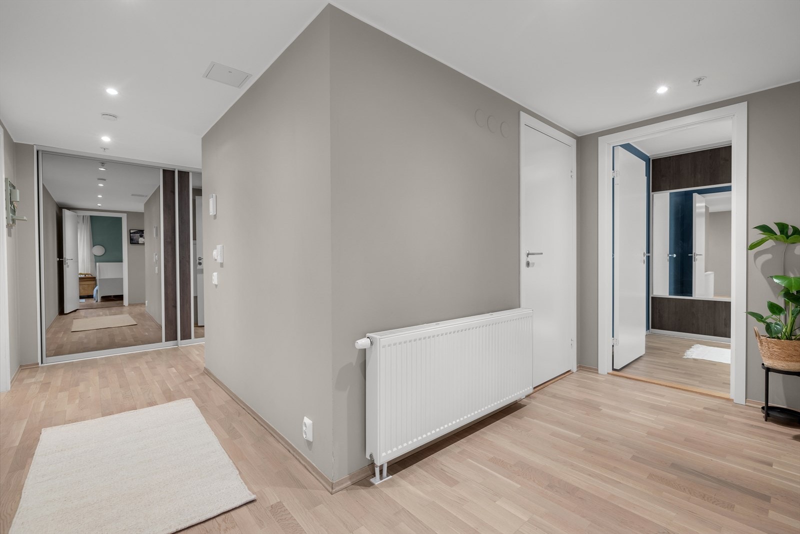 Stilren og innbydende entré i harmoniske grå- og beigetoner, belyst med downlights i himling. Galleribilde