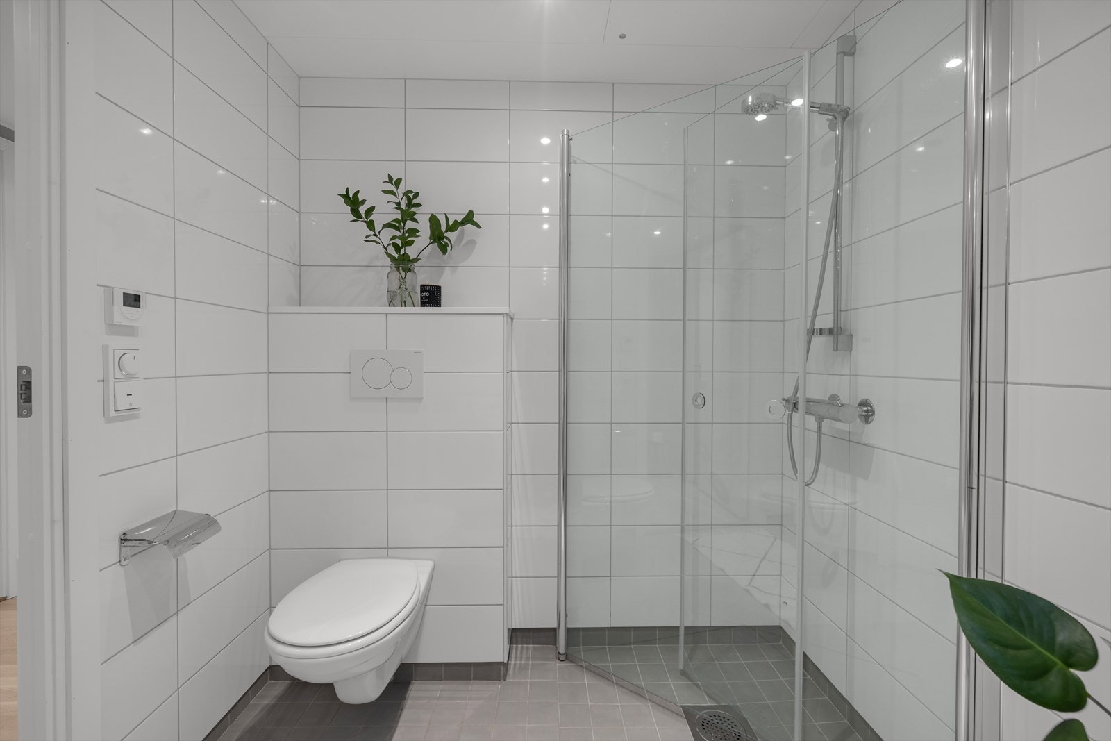 Badet er ellers innredet med stor dusjnisje med innfellbare glassdører, vegghengt wc, servant med oppbevaring i underskuffer, speil med lys, samt opplegg til både vaskemaskin og tørketrommel. Galleribilde
